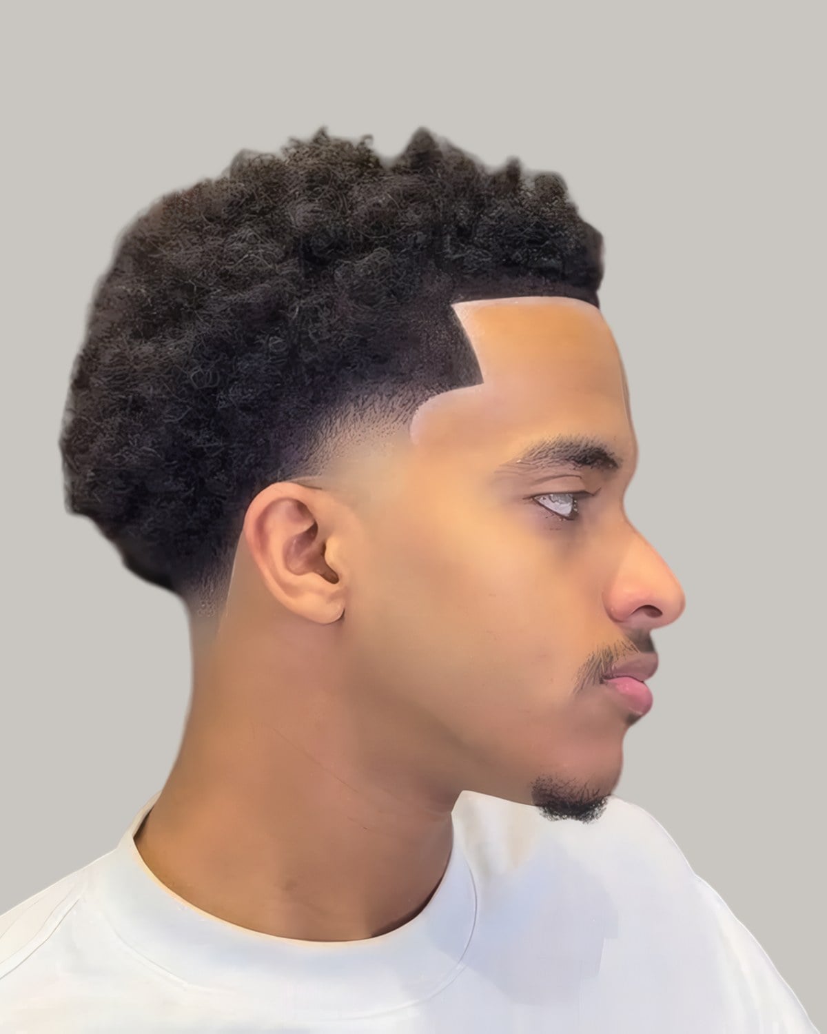 Young man with short tight curls and a sharp hairline, seen from the side