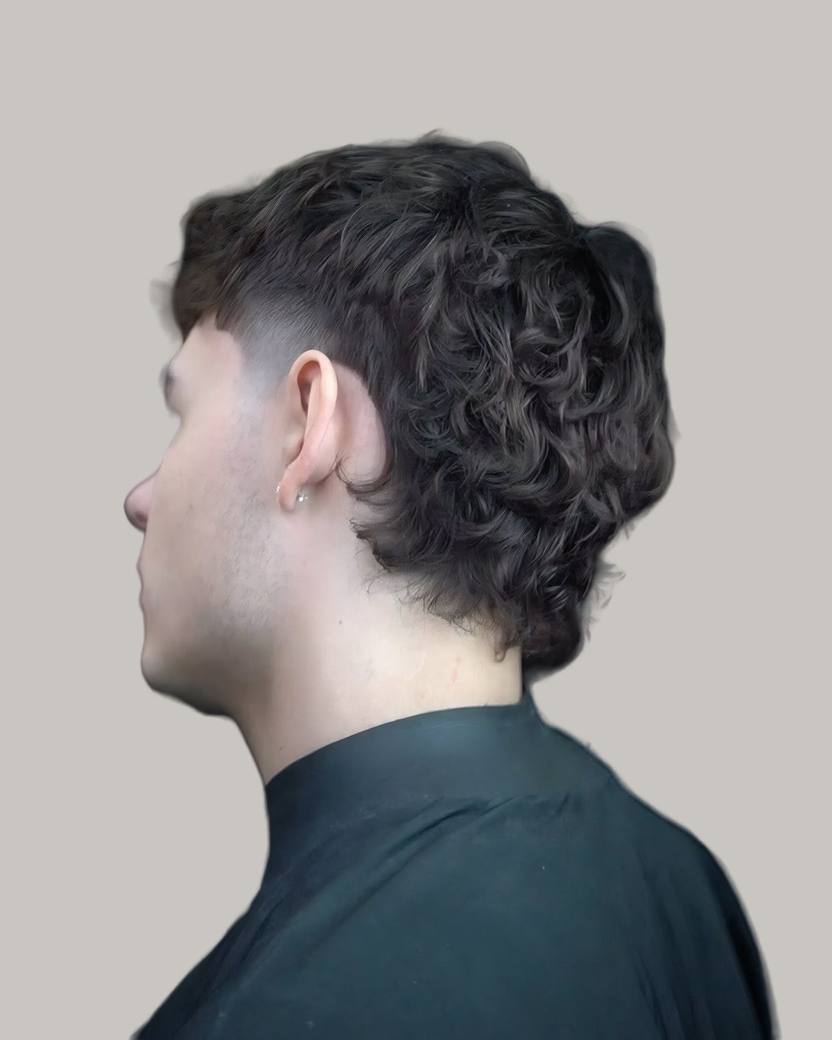 Man with a curly mullet and a taper, seen from behind at an angle