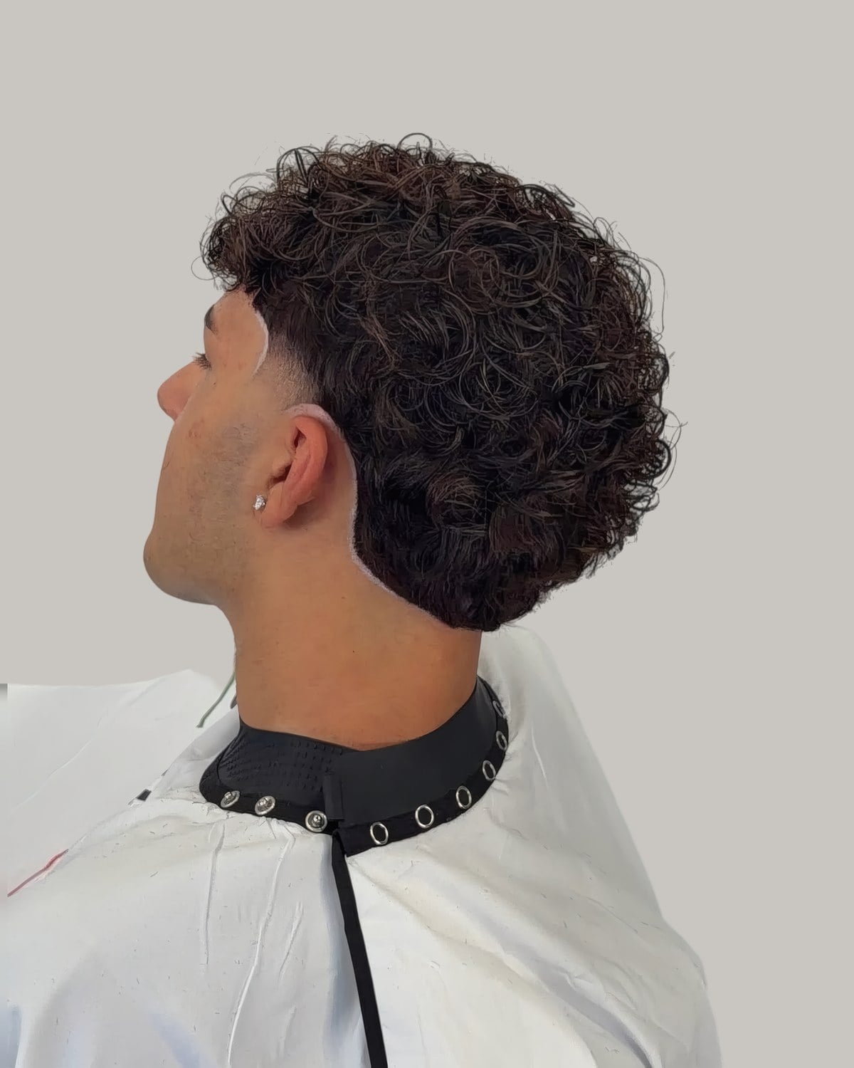 Man with dense curls and a taper, seen from behind at an angle