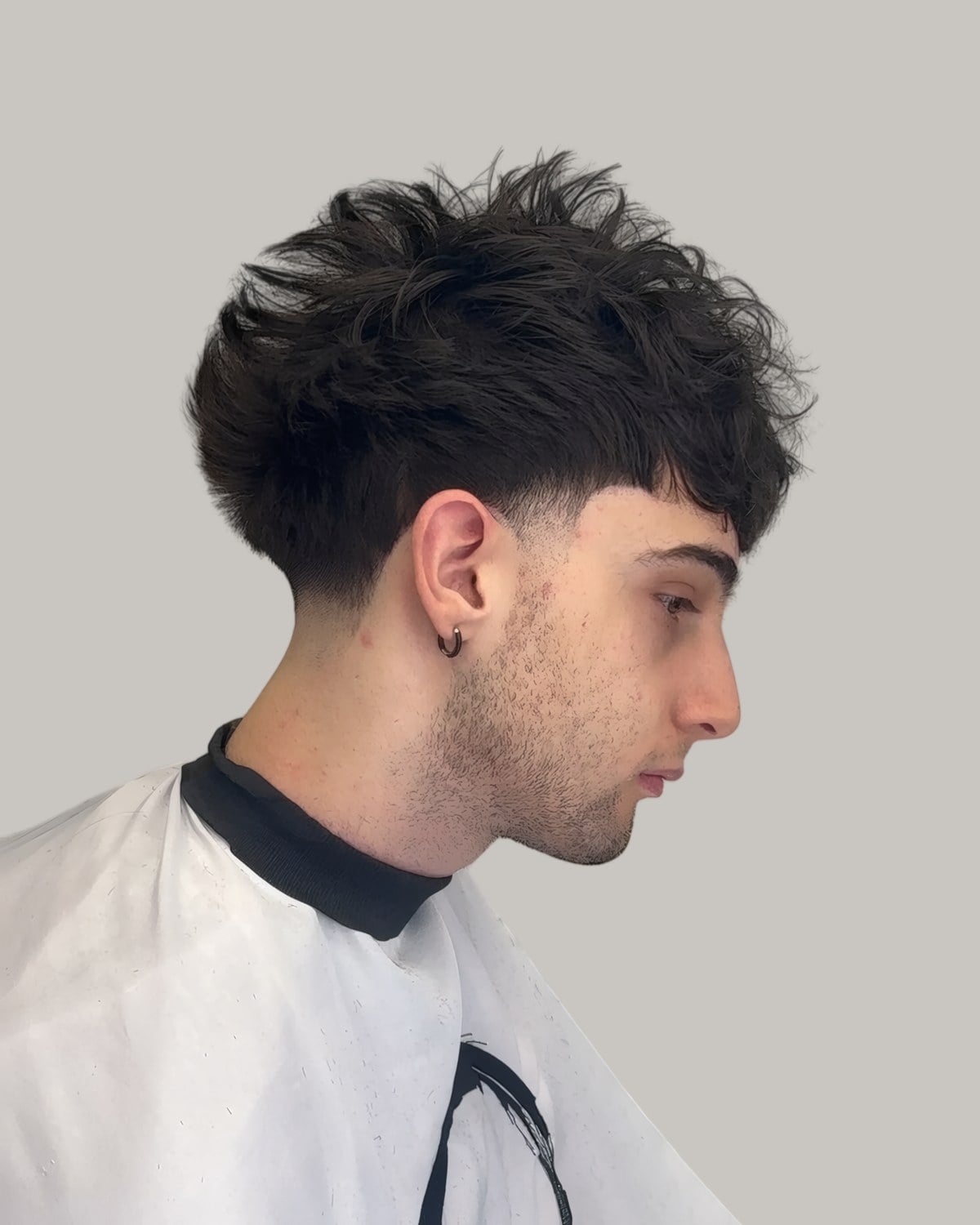 Man with a heavy textured fringe and a skin taper, seen in profile