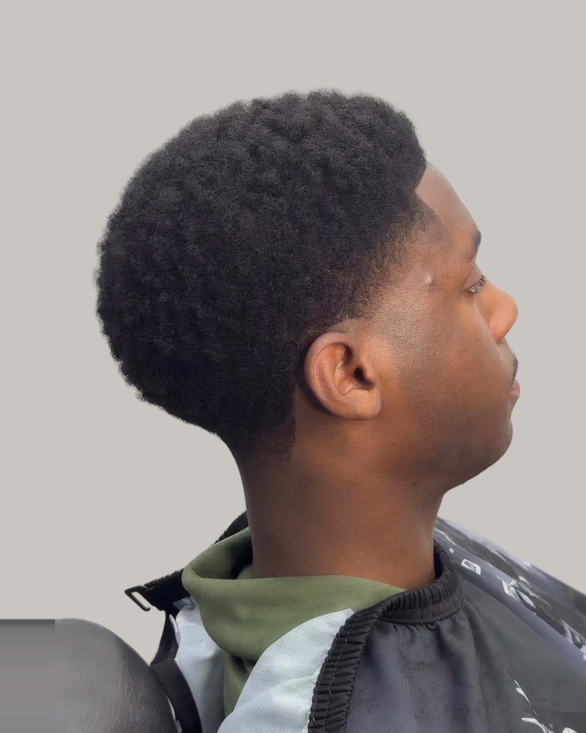 Young man with tight curls on top and a taper, seen in profile