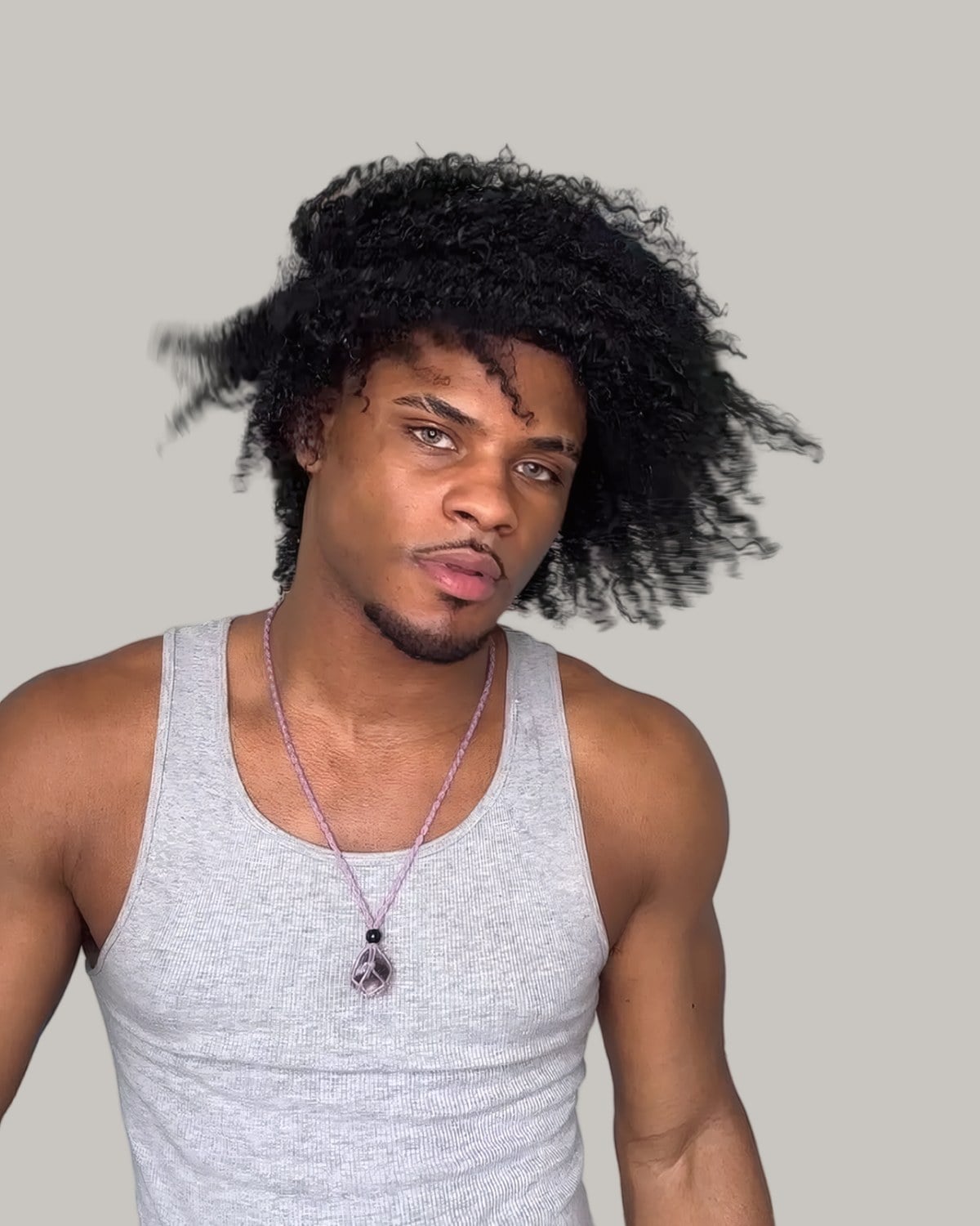 Man with a big loose afro and a tank top, seen from the front