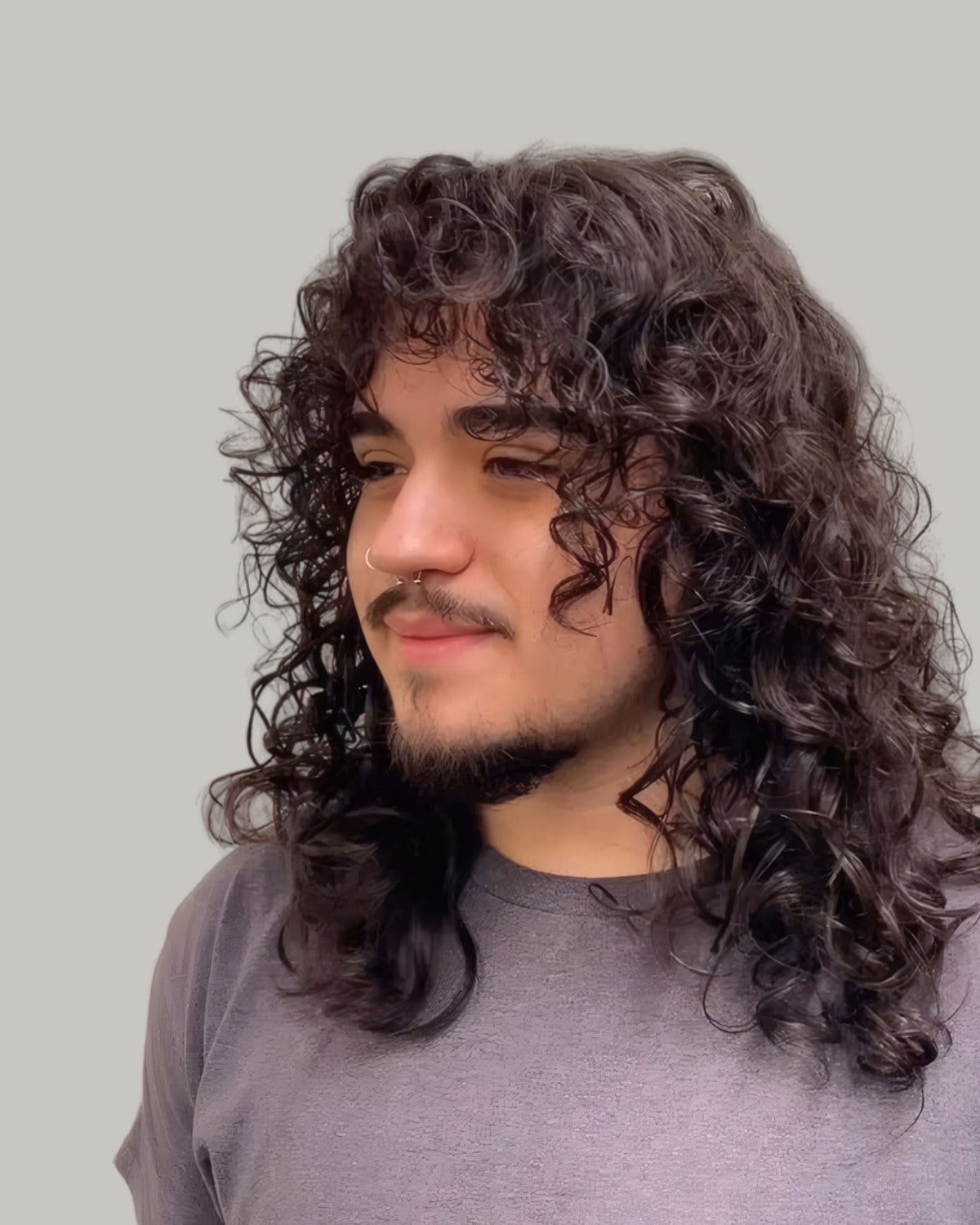 Young man with long dark ringlets past his shoulders, seen from the front at an angle