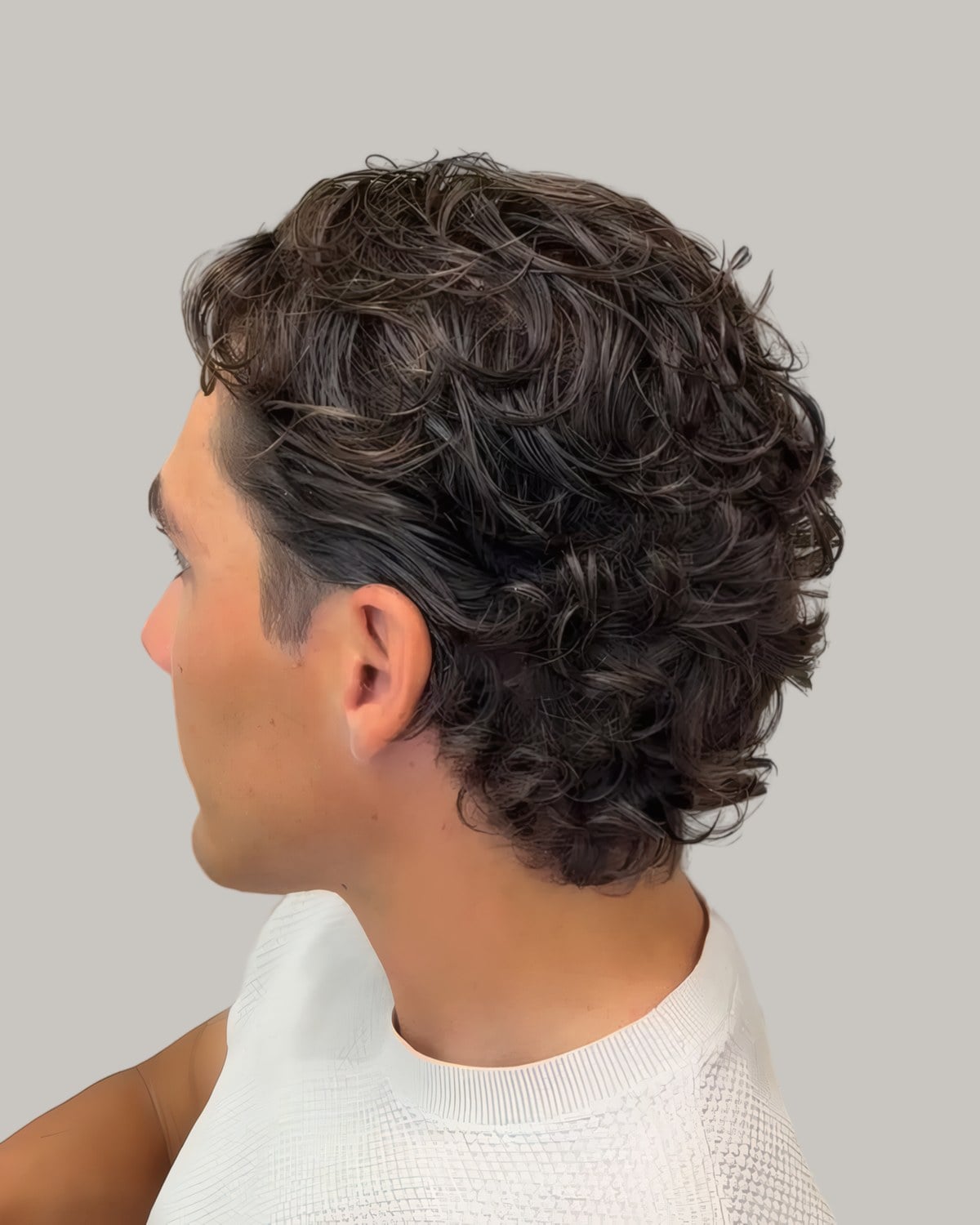 Man with long loose waves swept back, seen from behind at an angle