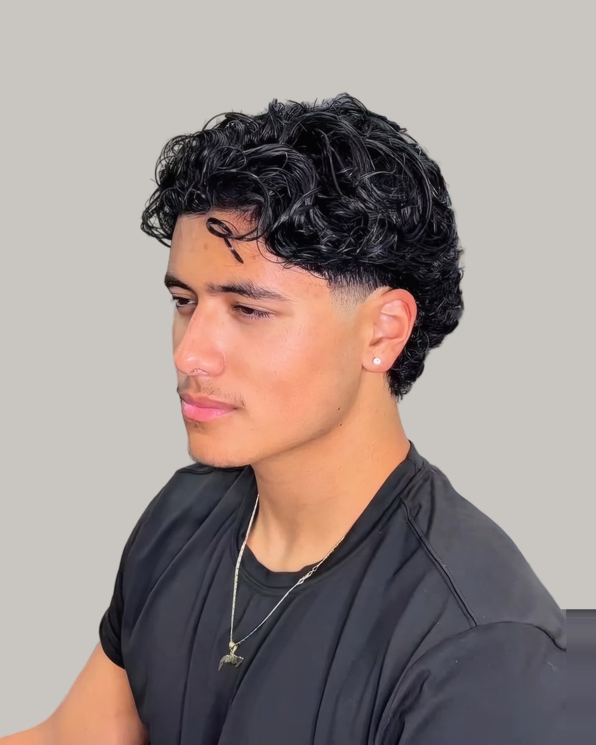 Young man with dark curls and a chain, seen from the front at an angle