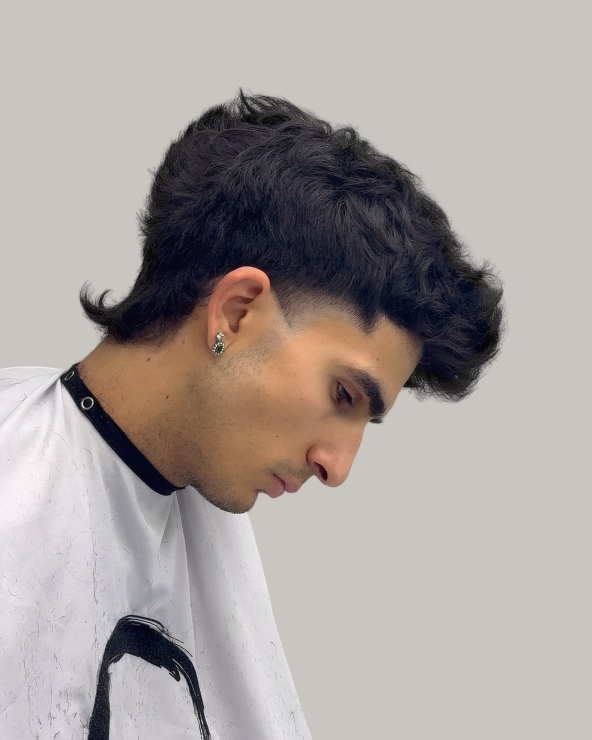 Man with a dark textured top pushed forward and a taper curving around the ear, seen in profile