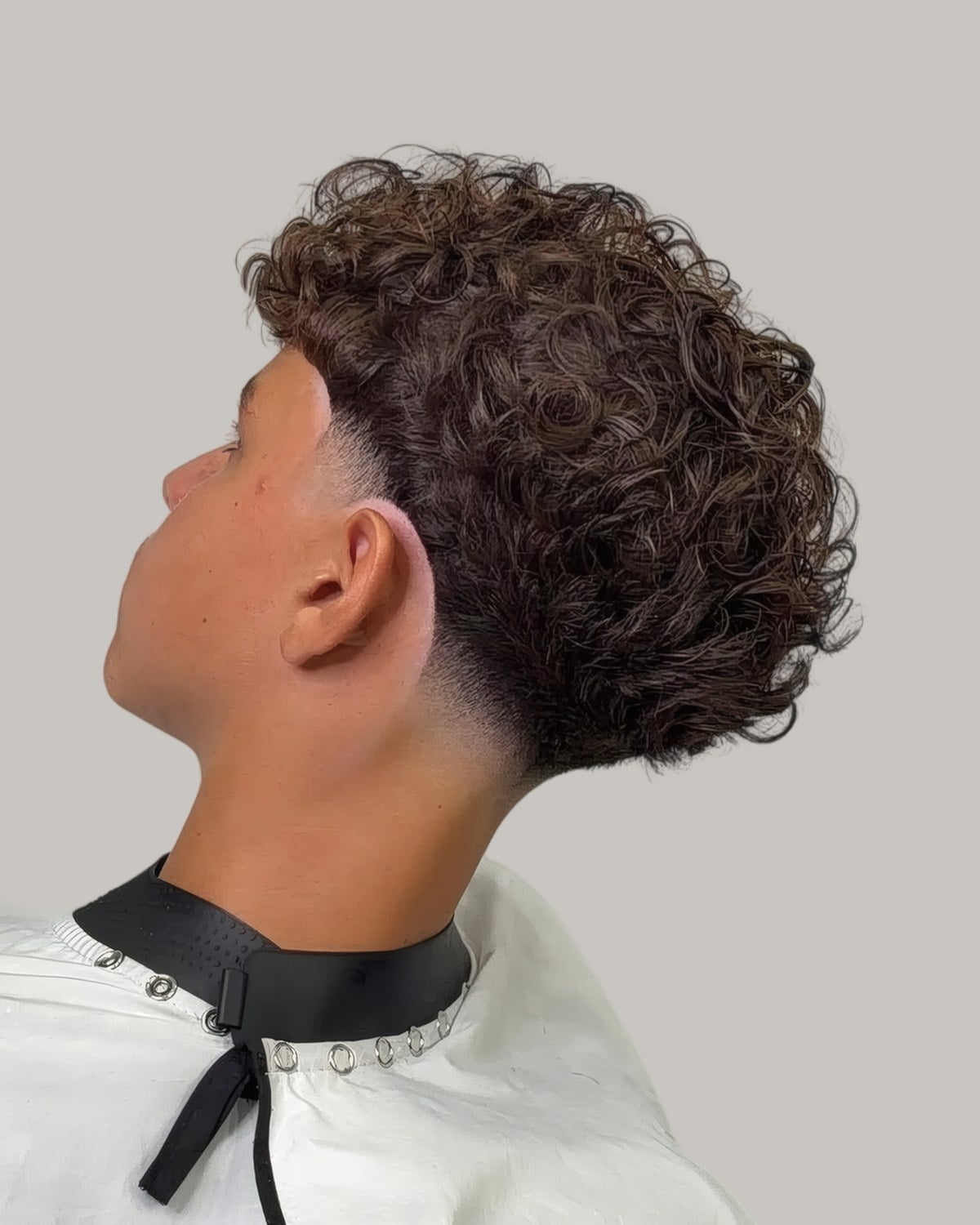 Man with a curly top and a fade, seen from behind at an angle