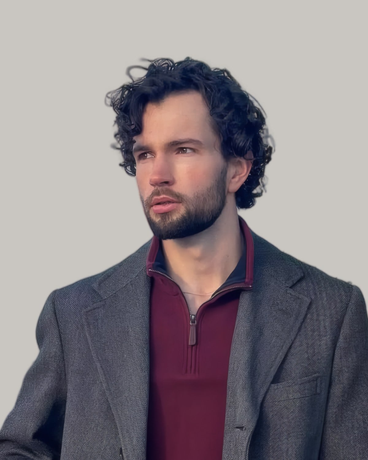Bearded man with medium curls and a blazer, seen from the front at an angle