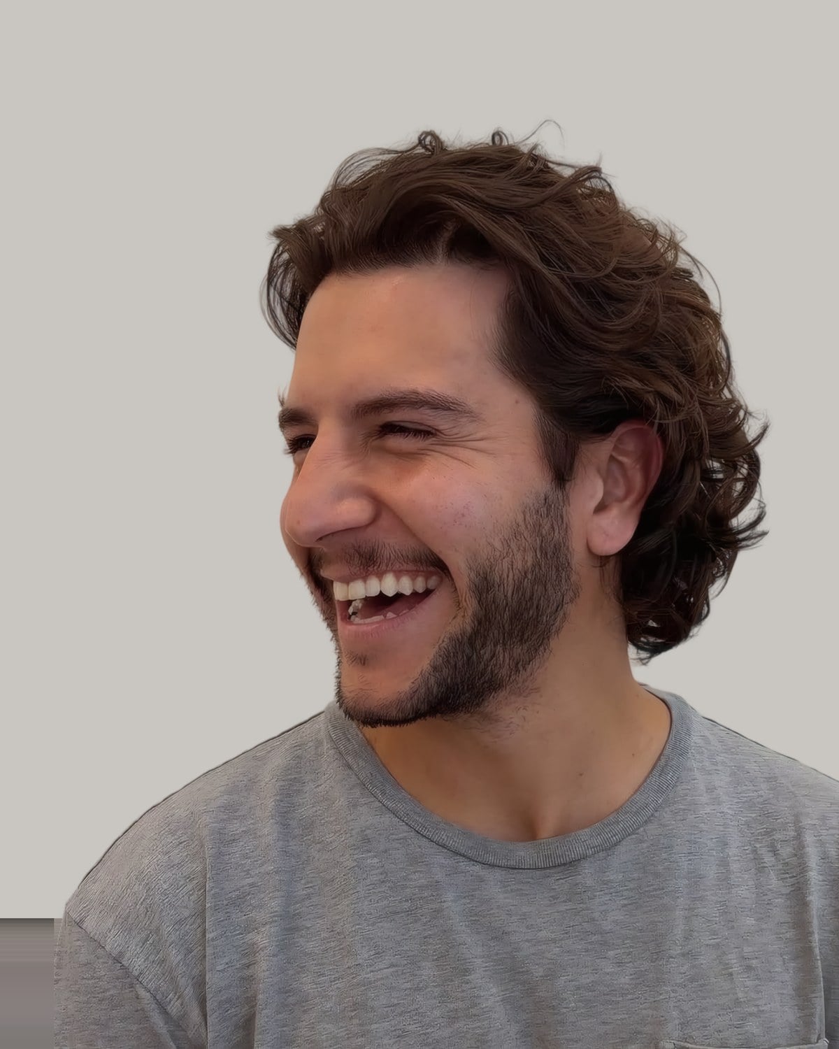Smiling man with dark wavy hair and a beard, seen from the side