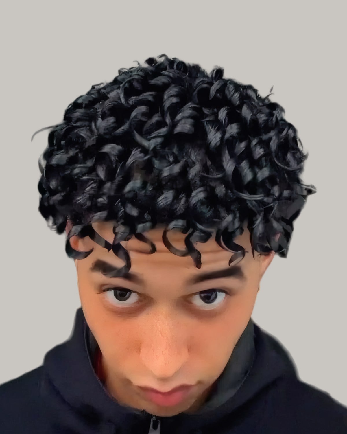 Young man with shiny dark curls falling over his forehead, looking down