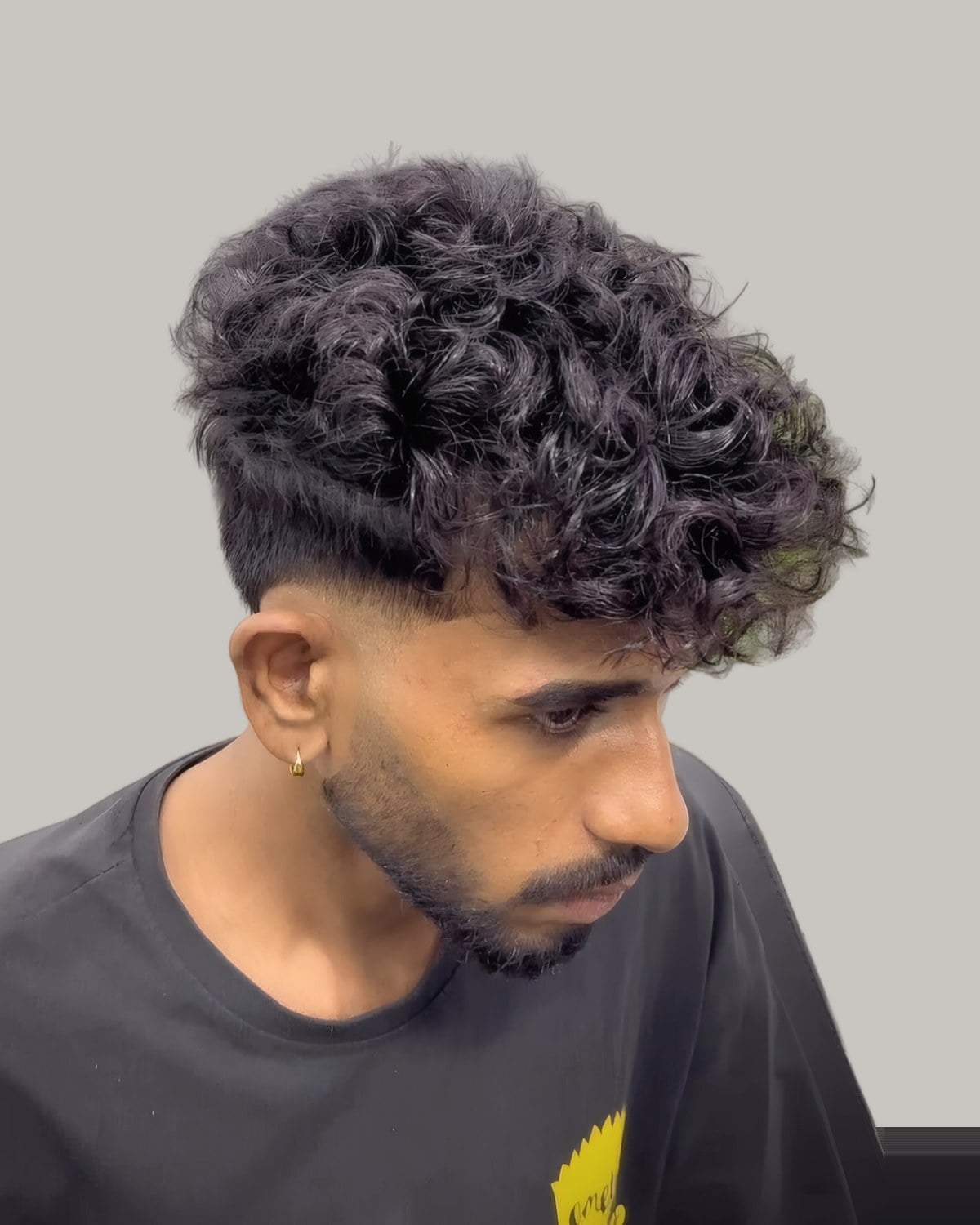 Bearded man with a curly top and a fade, seen from the front at an angle