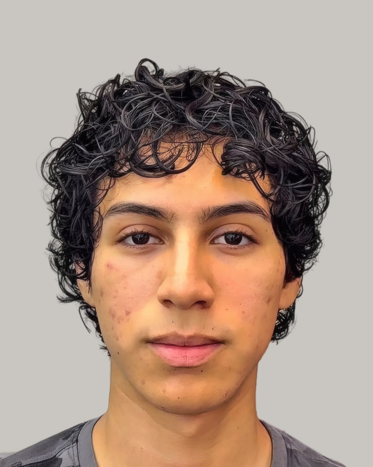 Young man with short loose curls and a soft fringe, seen from the front