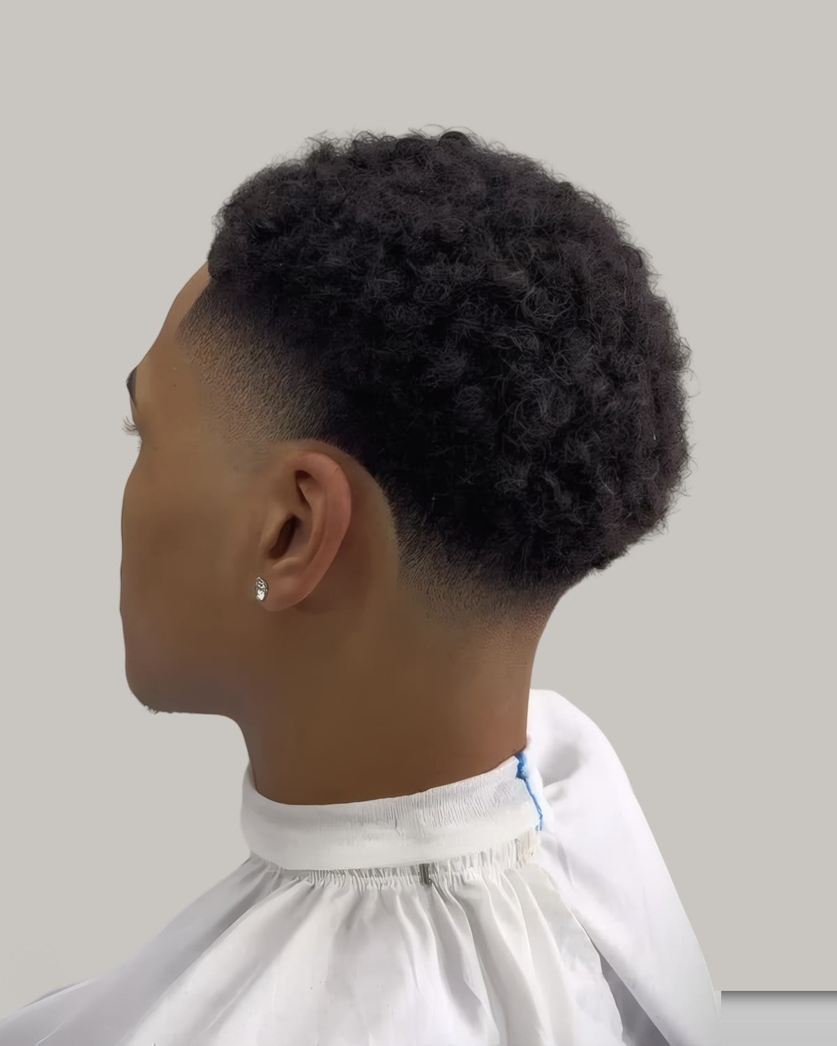 Man with short tight curls and a temple fade, seen in profile