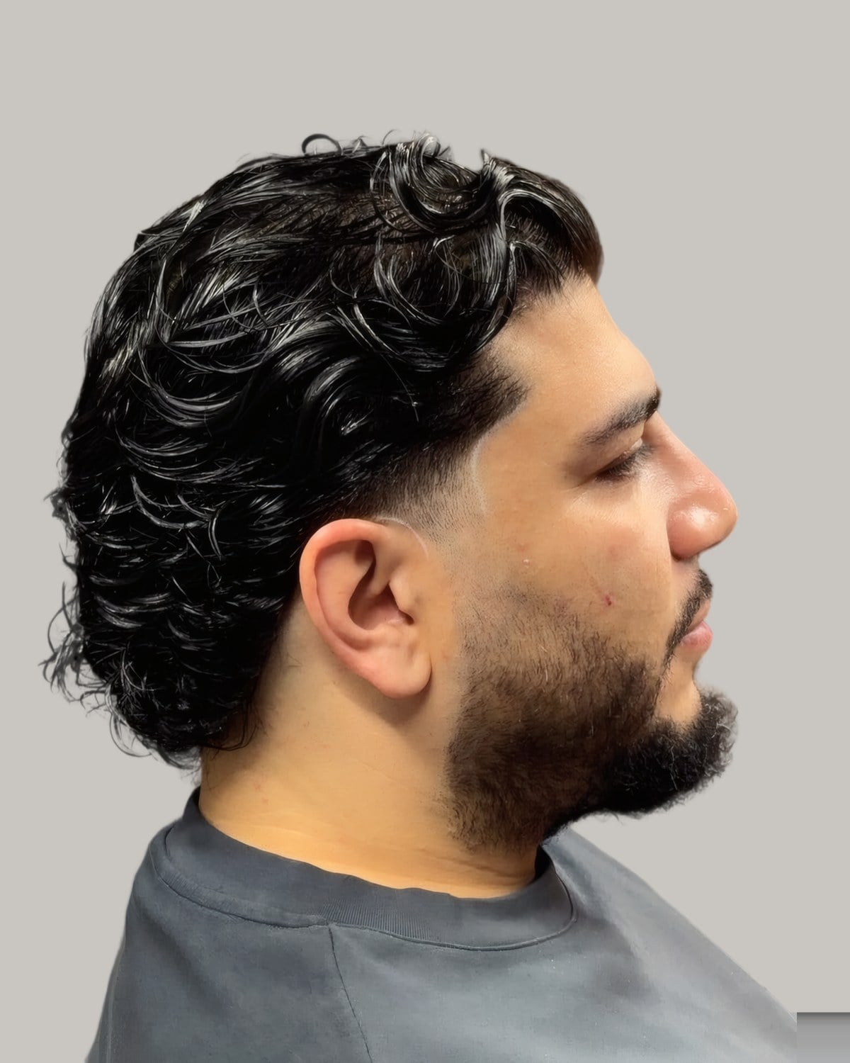 Bearded man with a curly top, seen from the side
