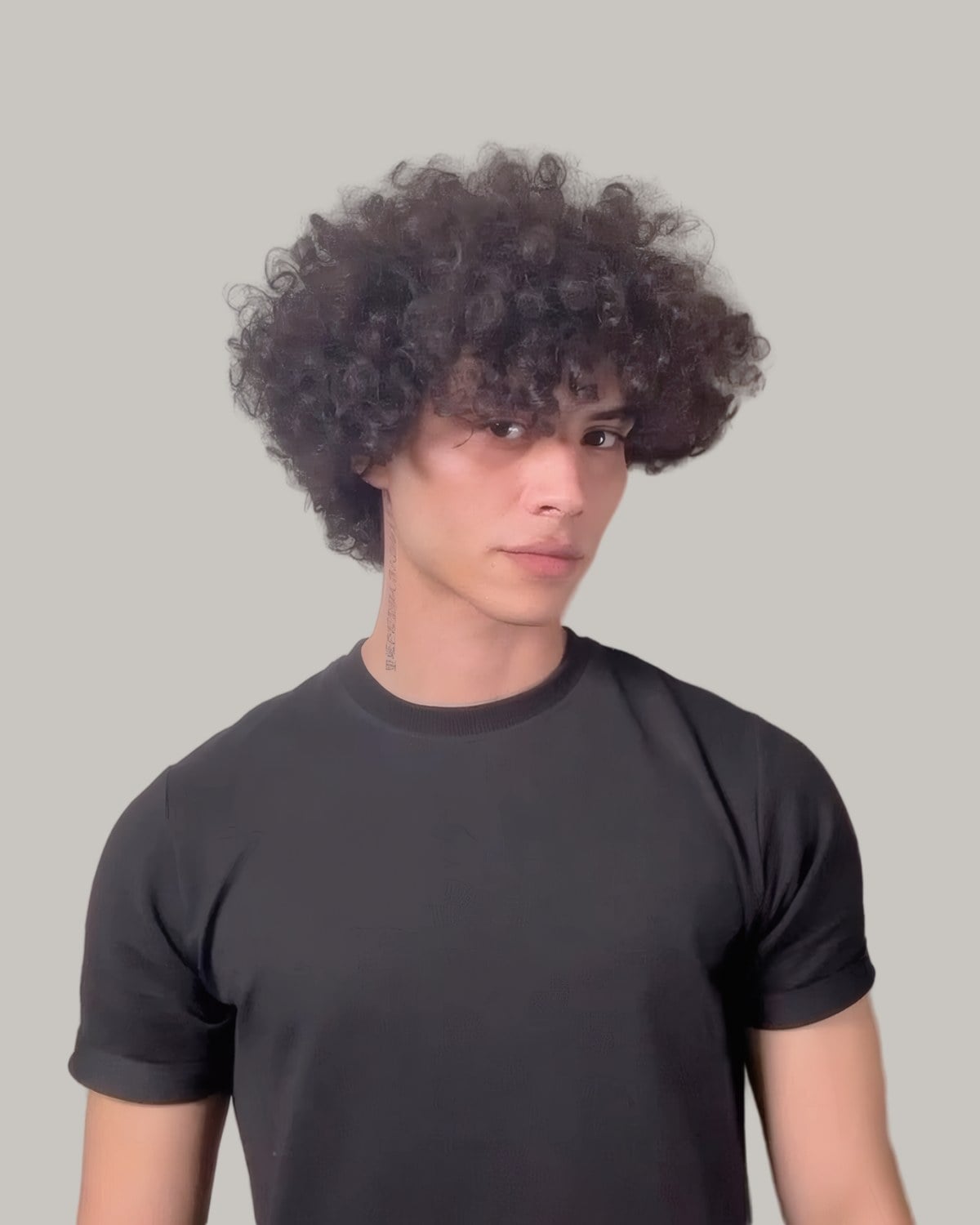 Young man with a loose afro top and short sides, seen from the front