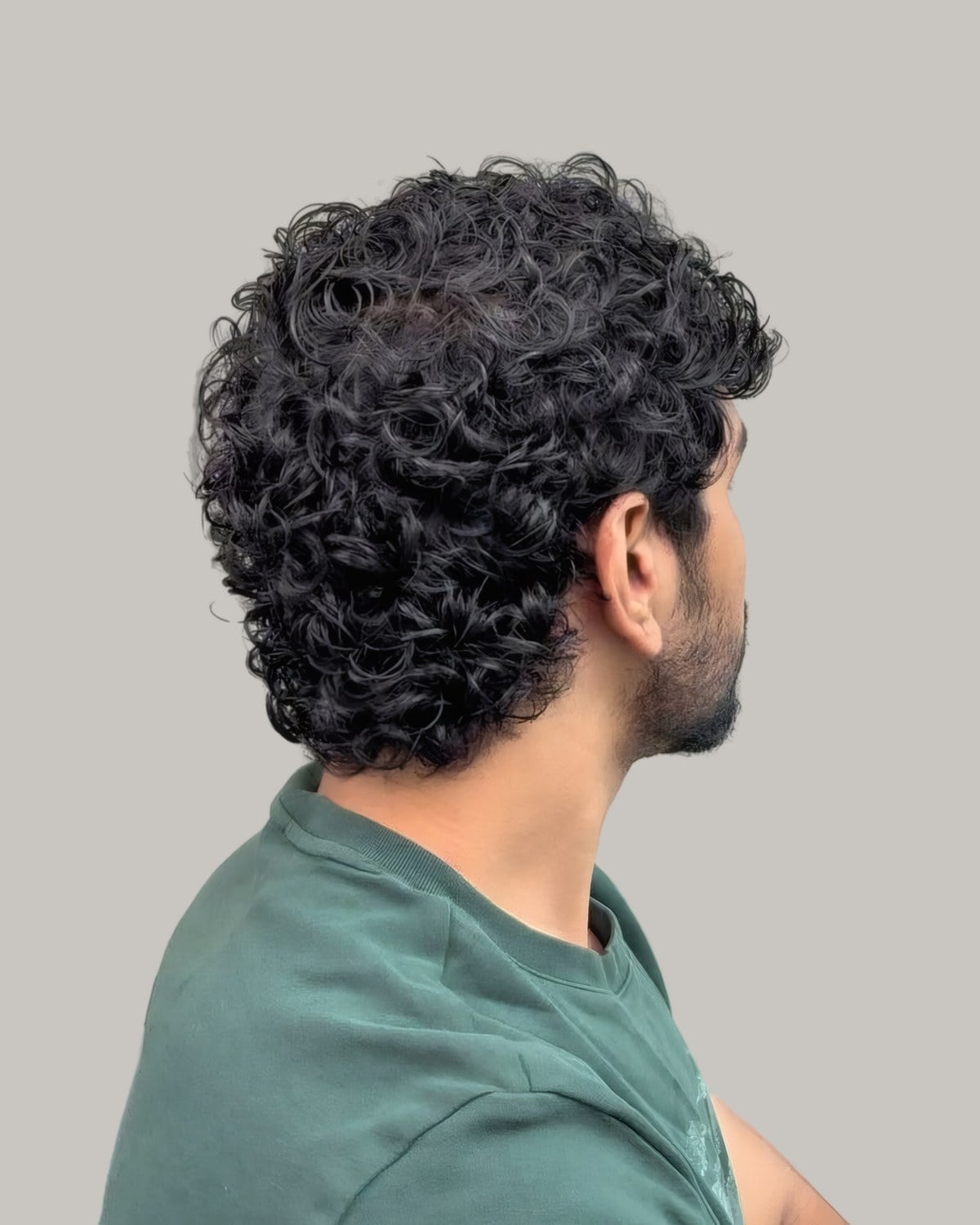 Man with dark curls and a green top, seen from the side
