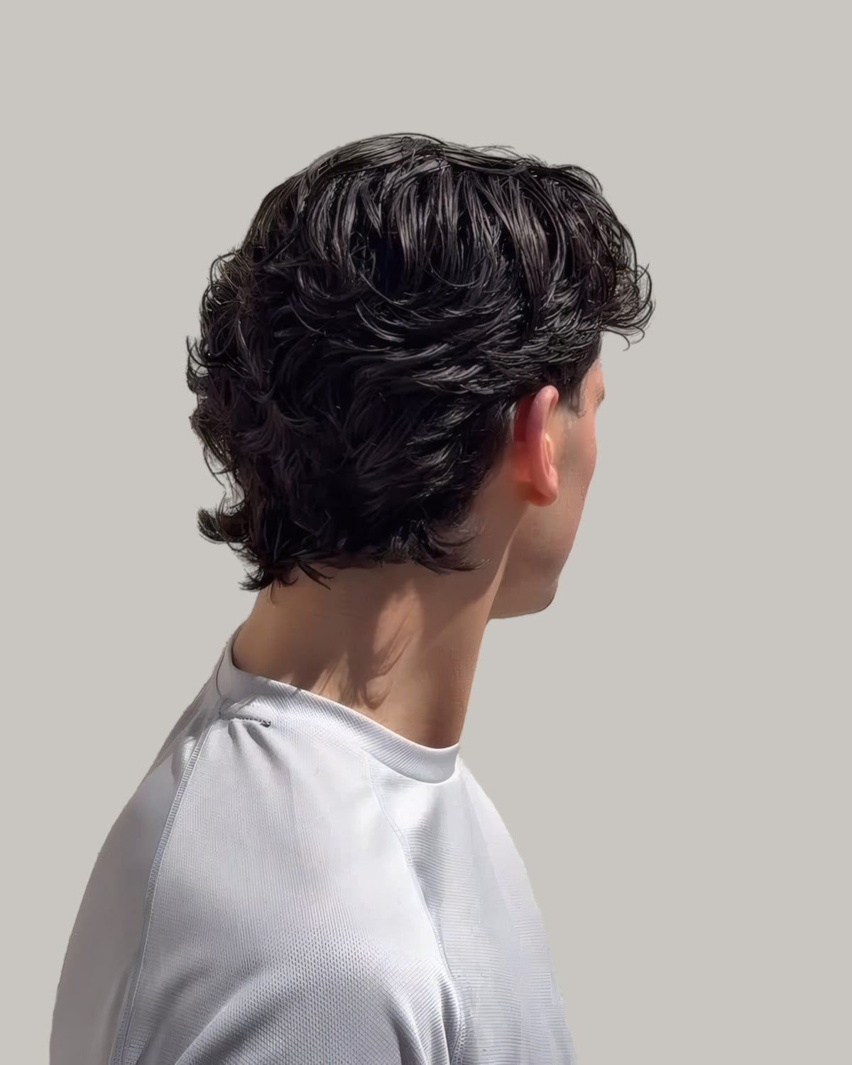 Man with a wavy mullet, seen from behind at an angle