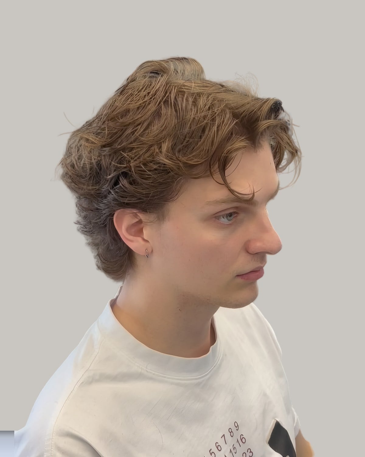 Young man with a tousled wavy top and short sides, seen in profile