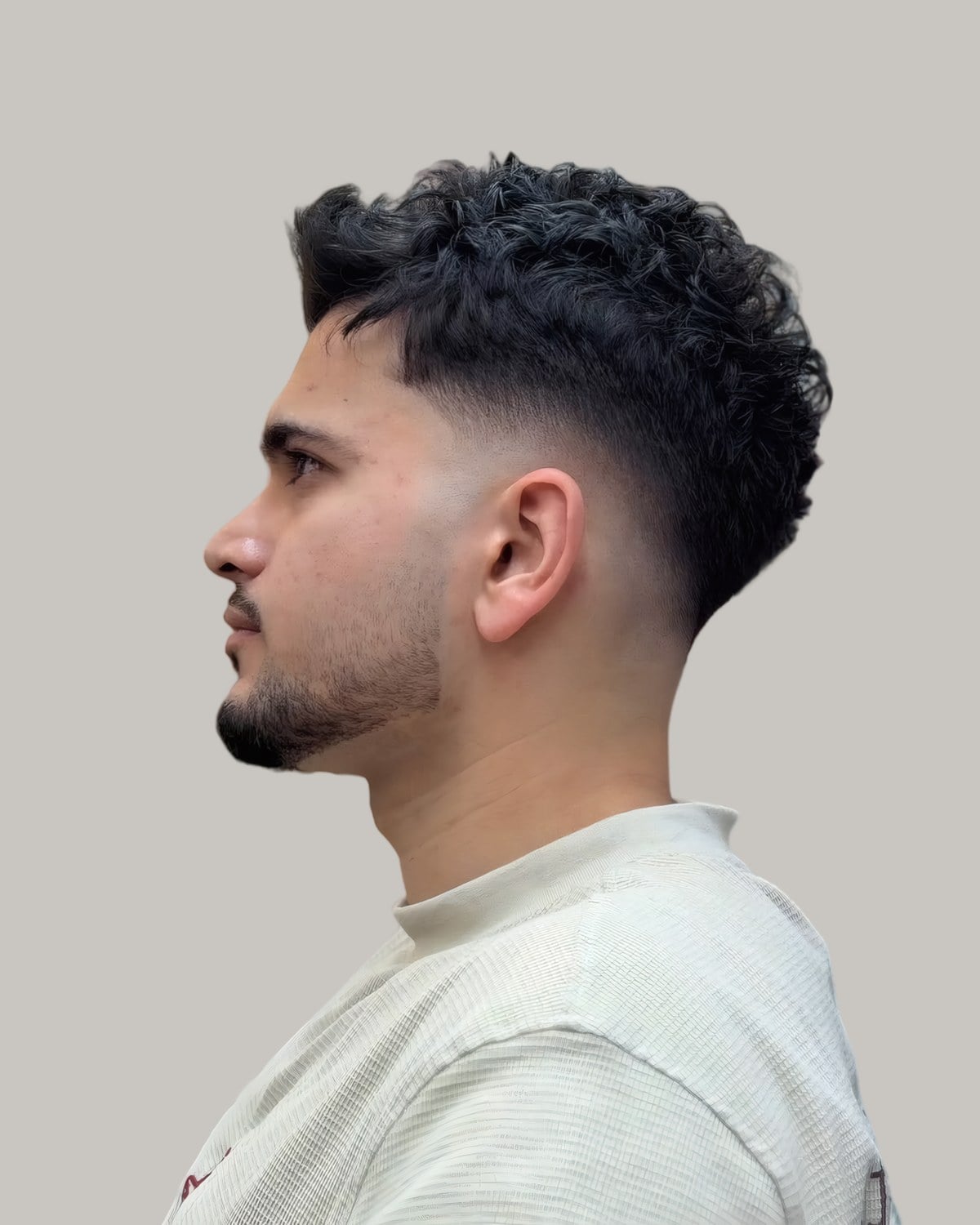 Man with a curly top and a fade, seen in profile