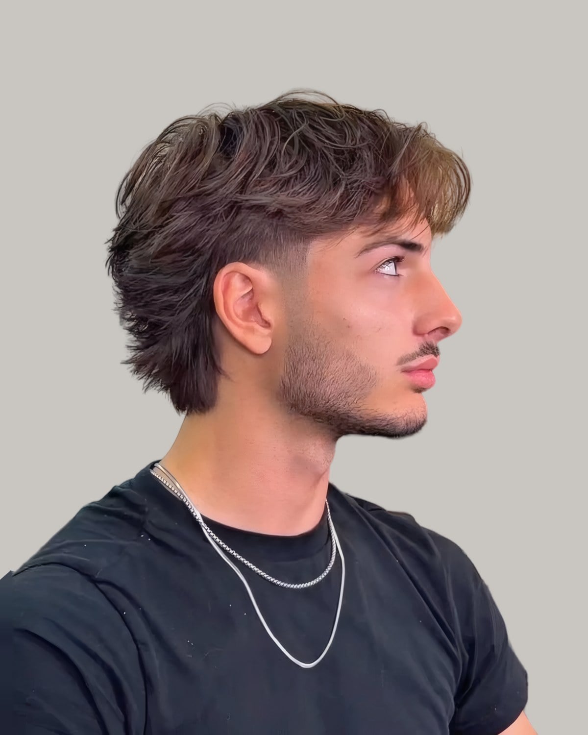 Man with a textured brown mullet and a mid taper at the temple, seen in profile