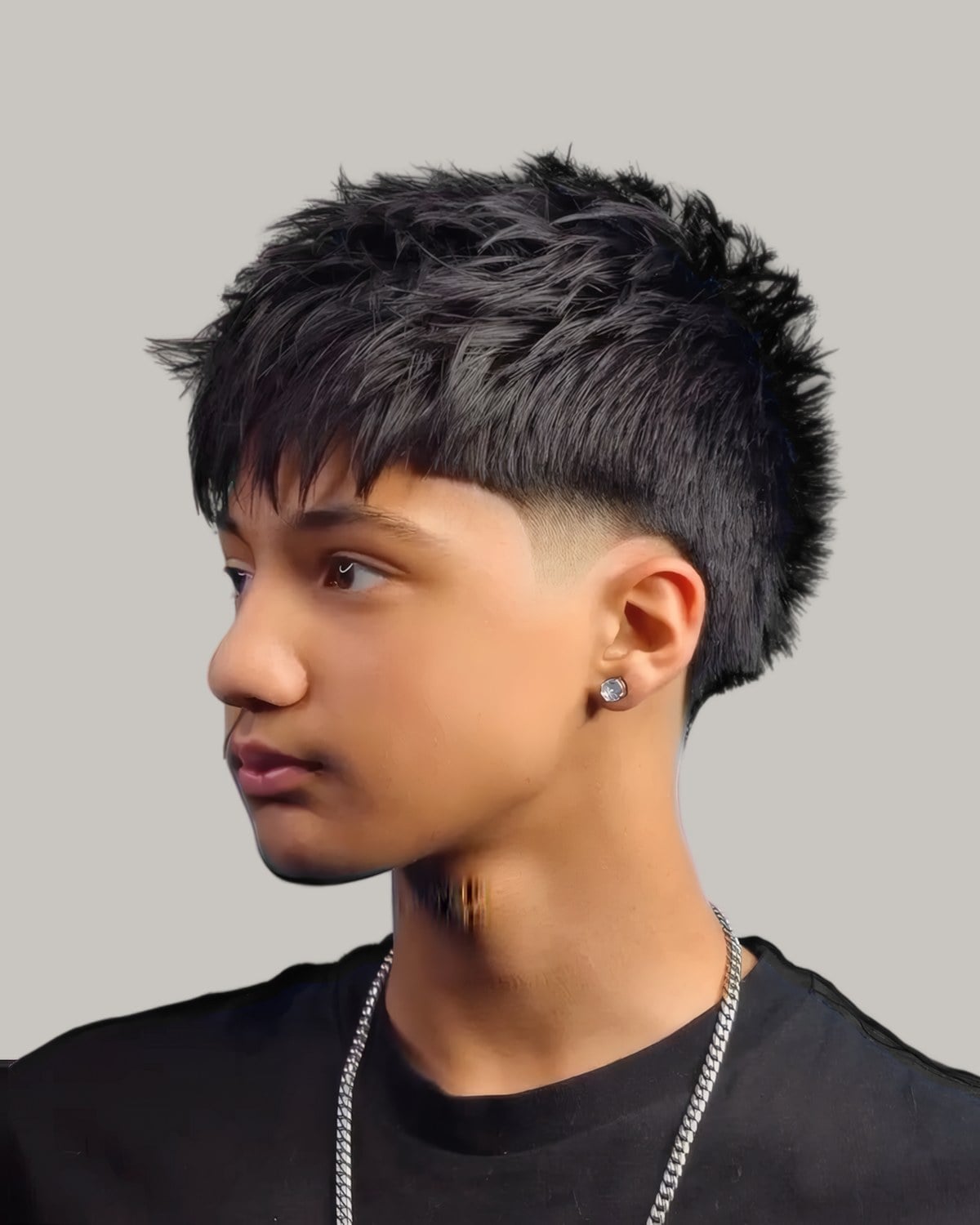 Young man with a dark textured fringe and a low taper, seen in profile