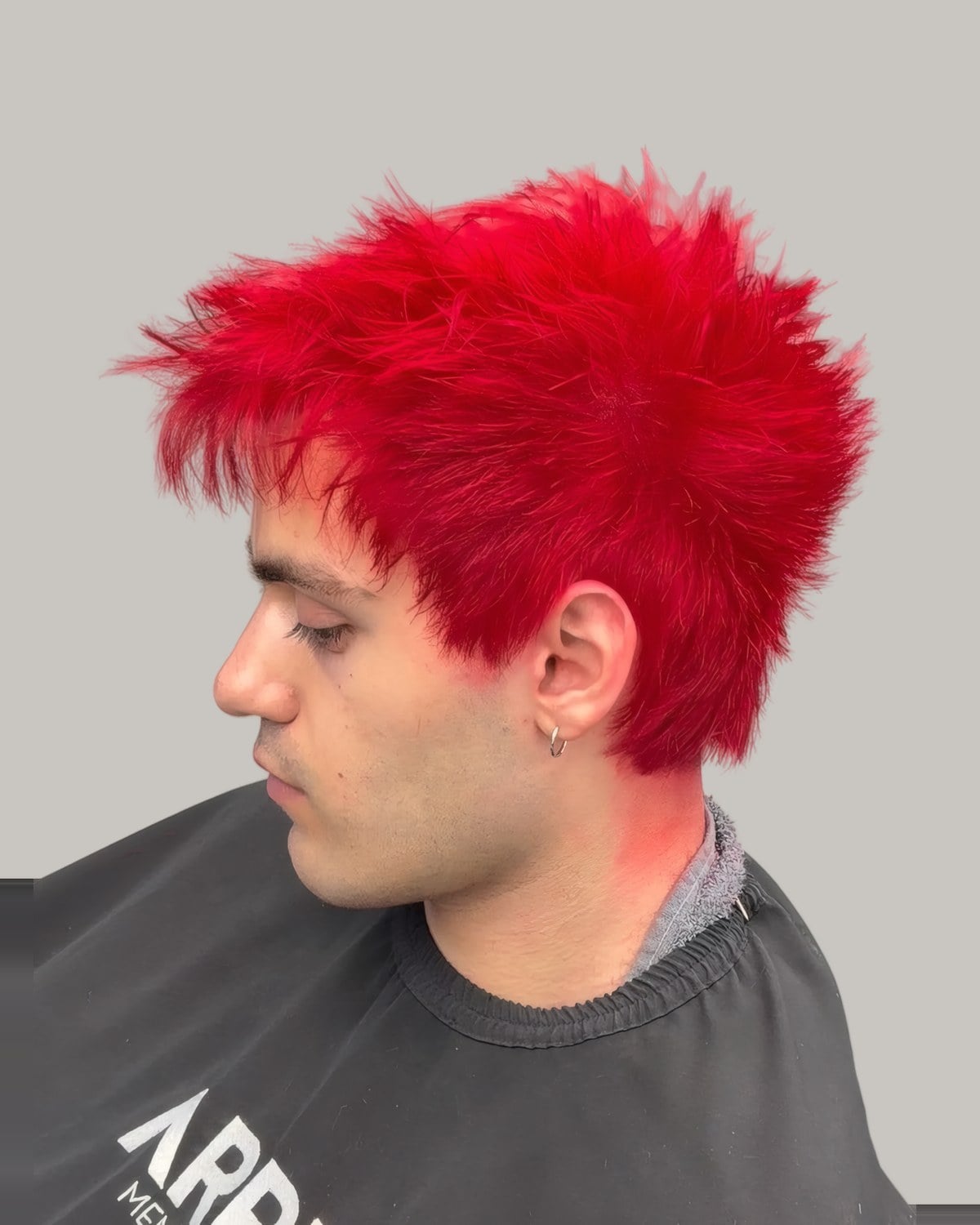 Man with bright red dyed hair and short sides, seen from the side