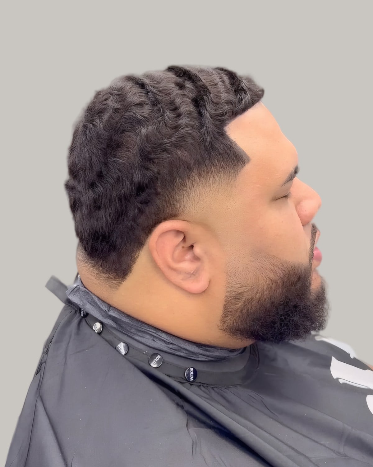 Bearded man with short twists on top and a low fade, seen from the side