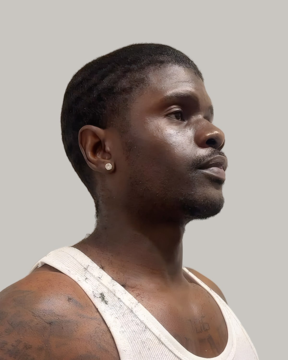 Man in a white tank top with short waves and faded sides, seen from the side