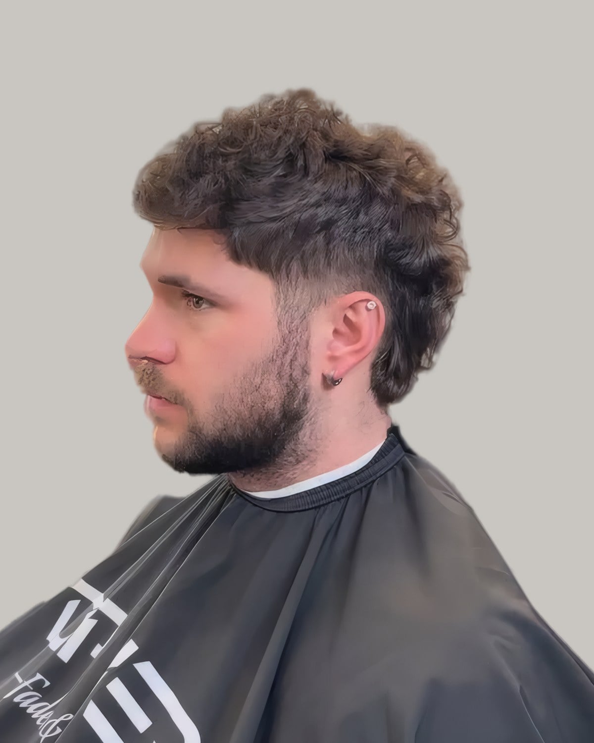 Bearded man with loose curls falling forward and a low fade, seen at an angle