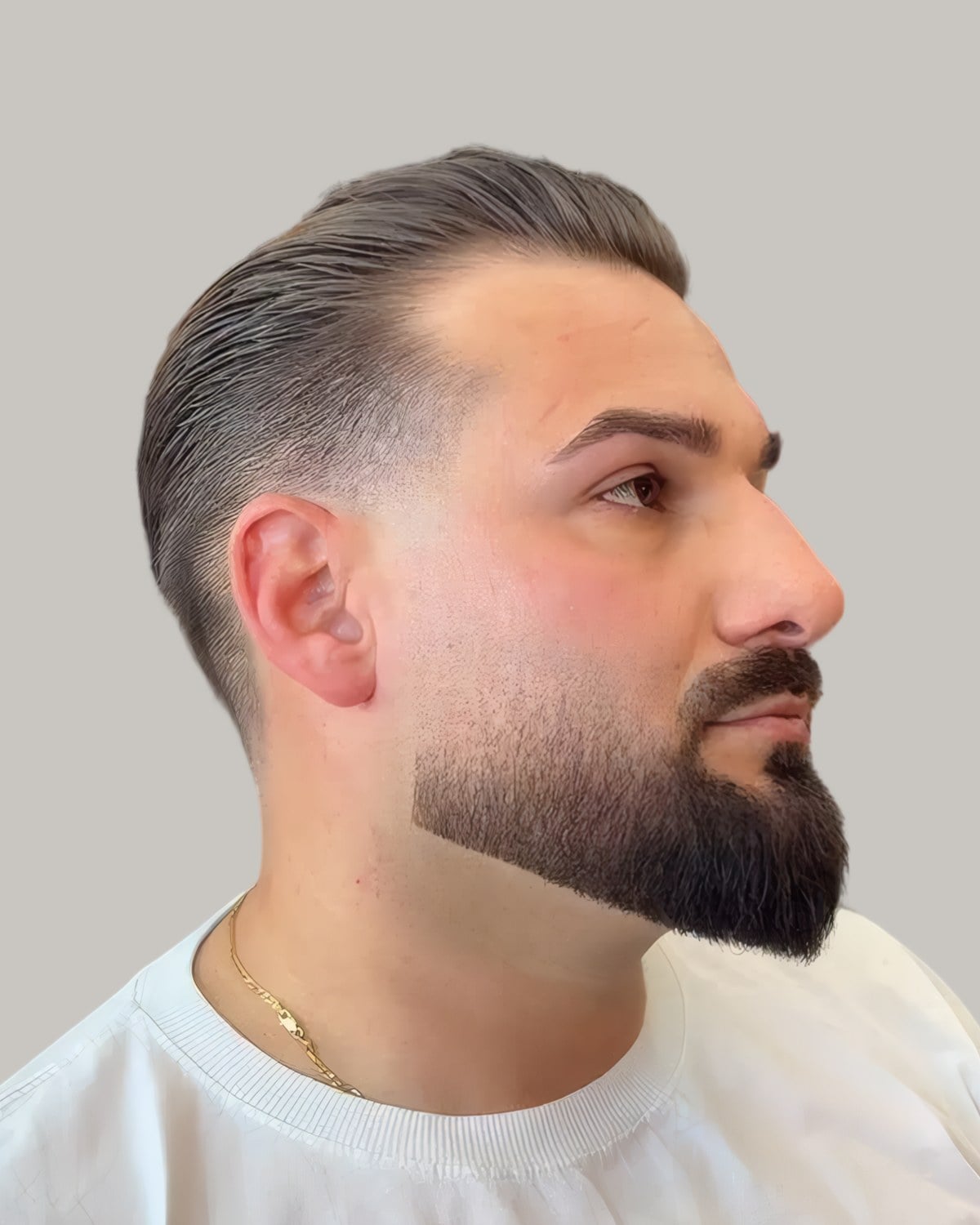Bearded man with a slicked side part and a mid fade, seen in profile