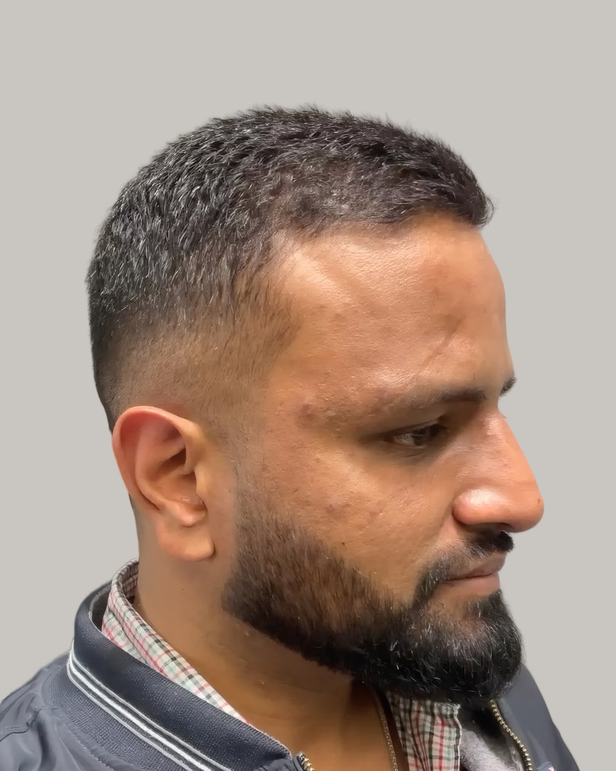 Bearded man with a short textured crop and a fade, seen at an angle
