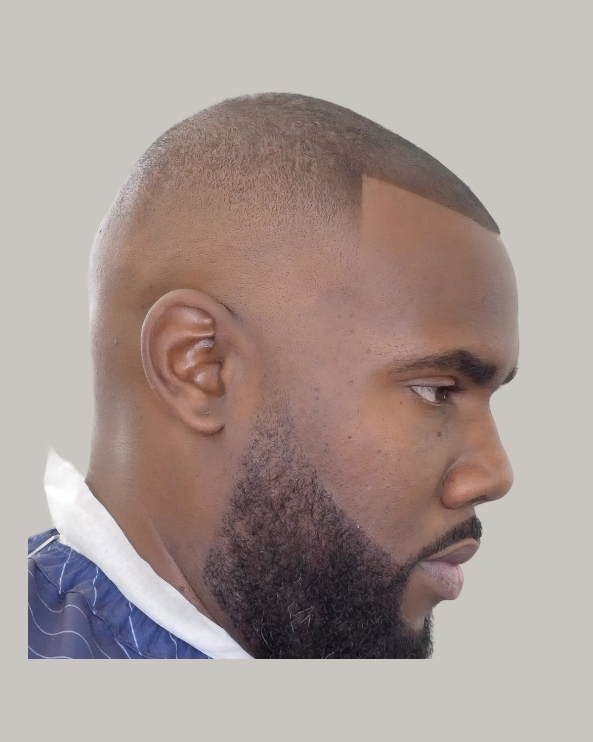 Man with a short low cut, a soft line-up and a full beard, seen in profile