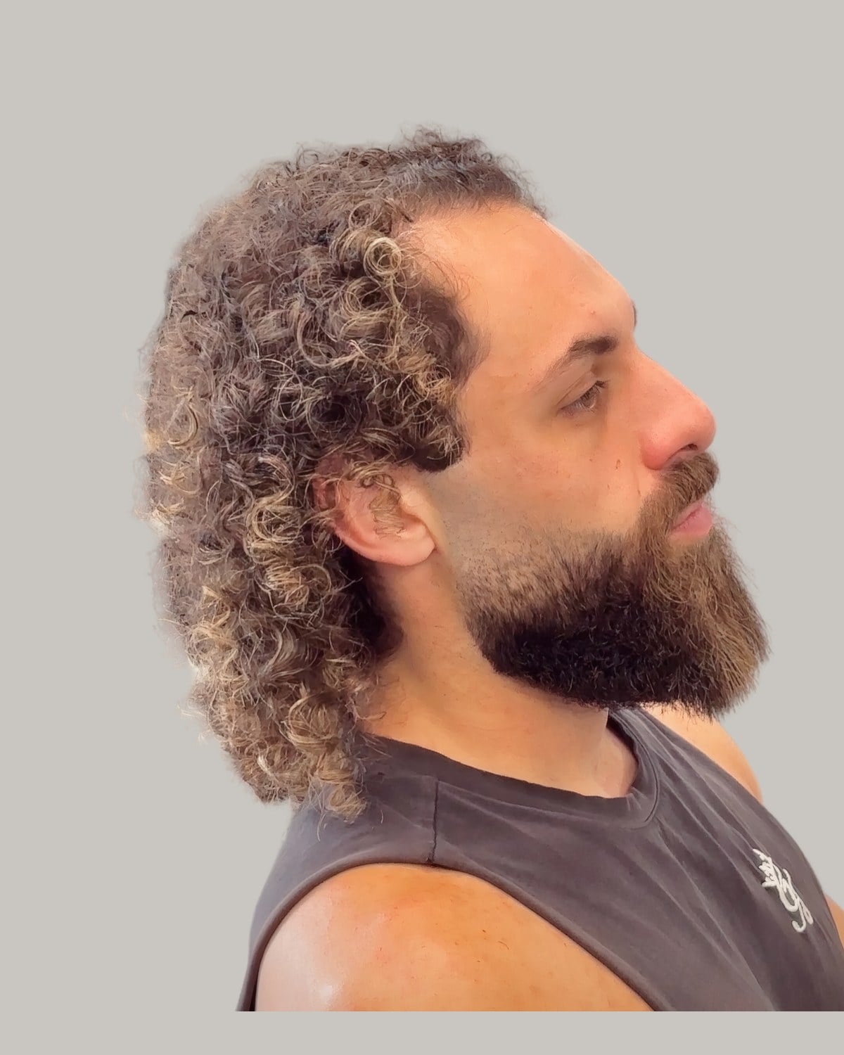 Bearded man with long curly hair and a high hairline, seen in profile