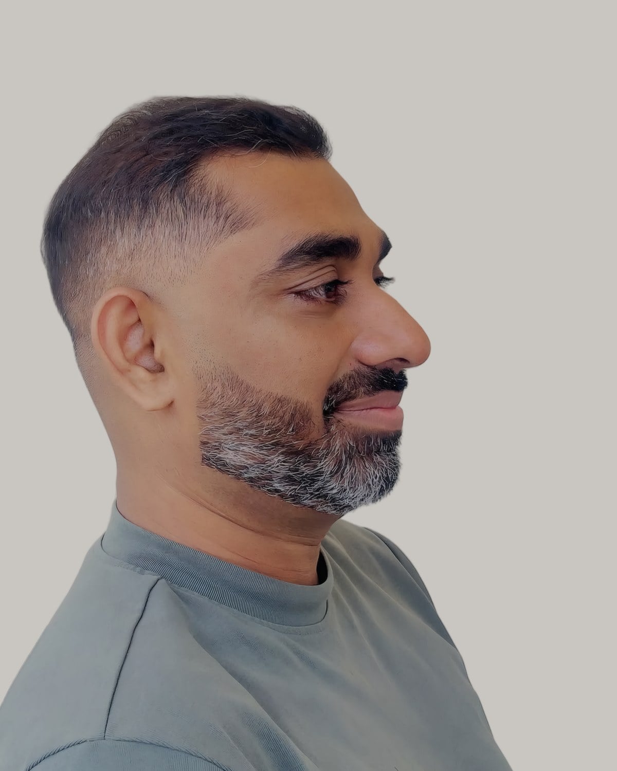Bearded man with a low taper fade and a grey beard, seen at an angle