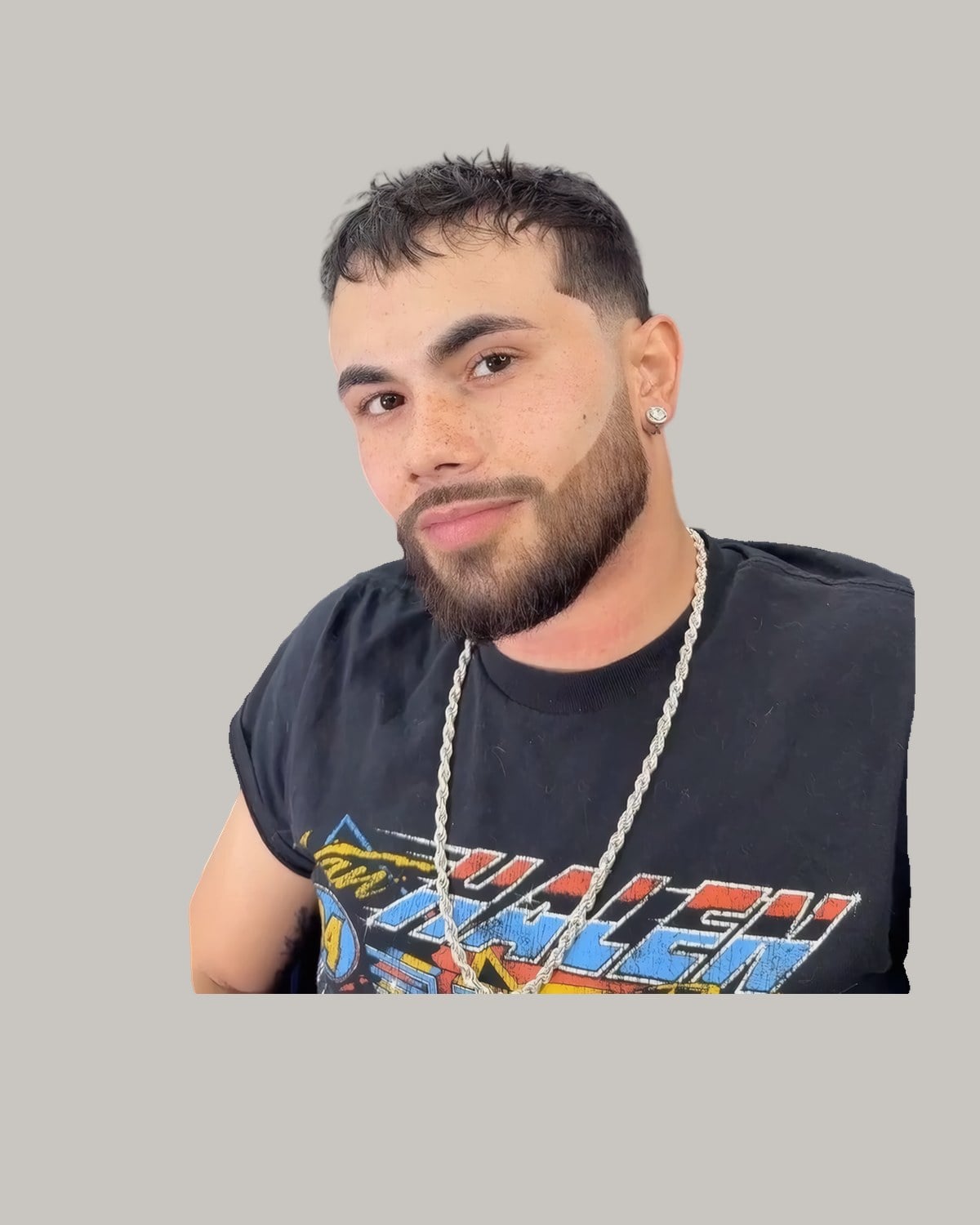 Bearded man with a short messy fringe, a chain necklace and a graphic T-shirt