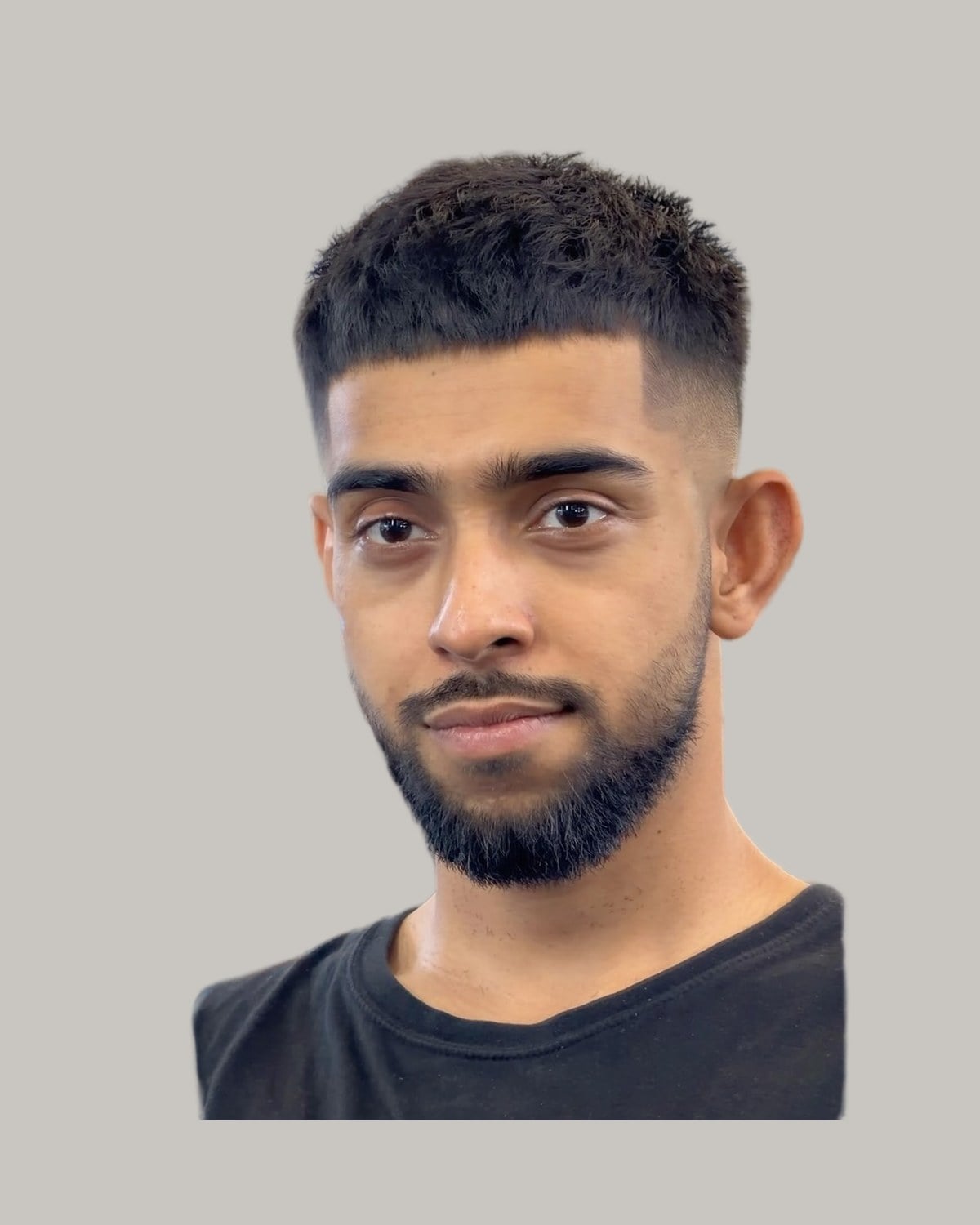 Bearded man with a textured crop and a mid fade, seen from the front