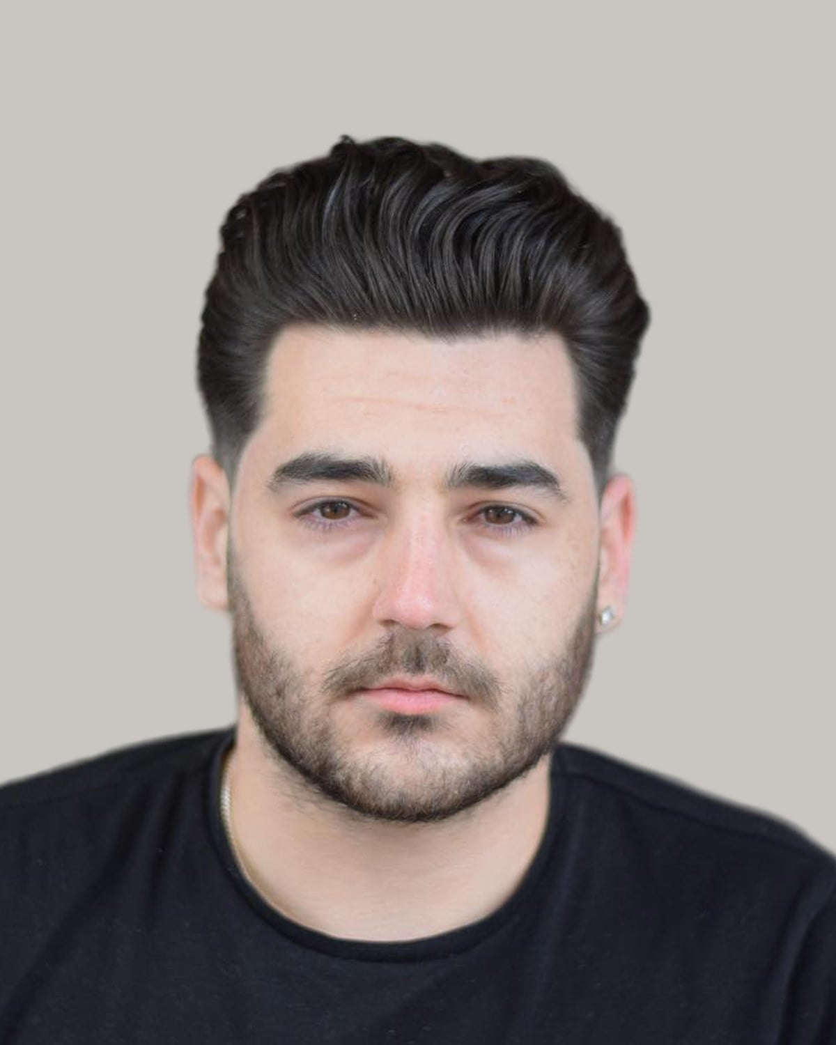 Man with a dark pompadour, tapered sides and a short beard, in a black T-shirt