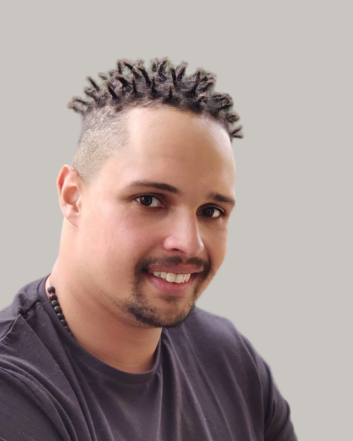 Smiling man with short twists on top, faded sides and a goatee, outdoors