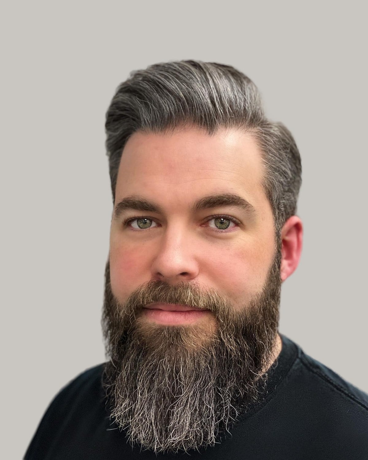 Man with graying hair swept back and to one side, and a long, full beard flecked with gray