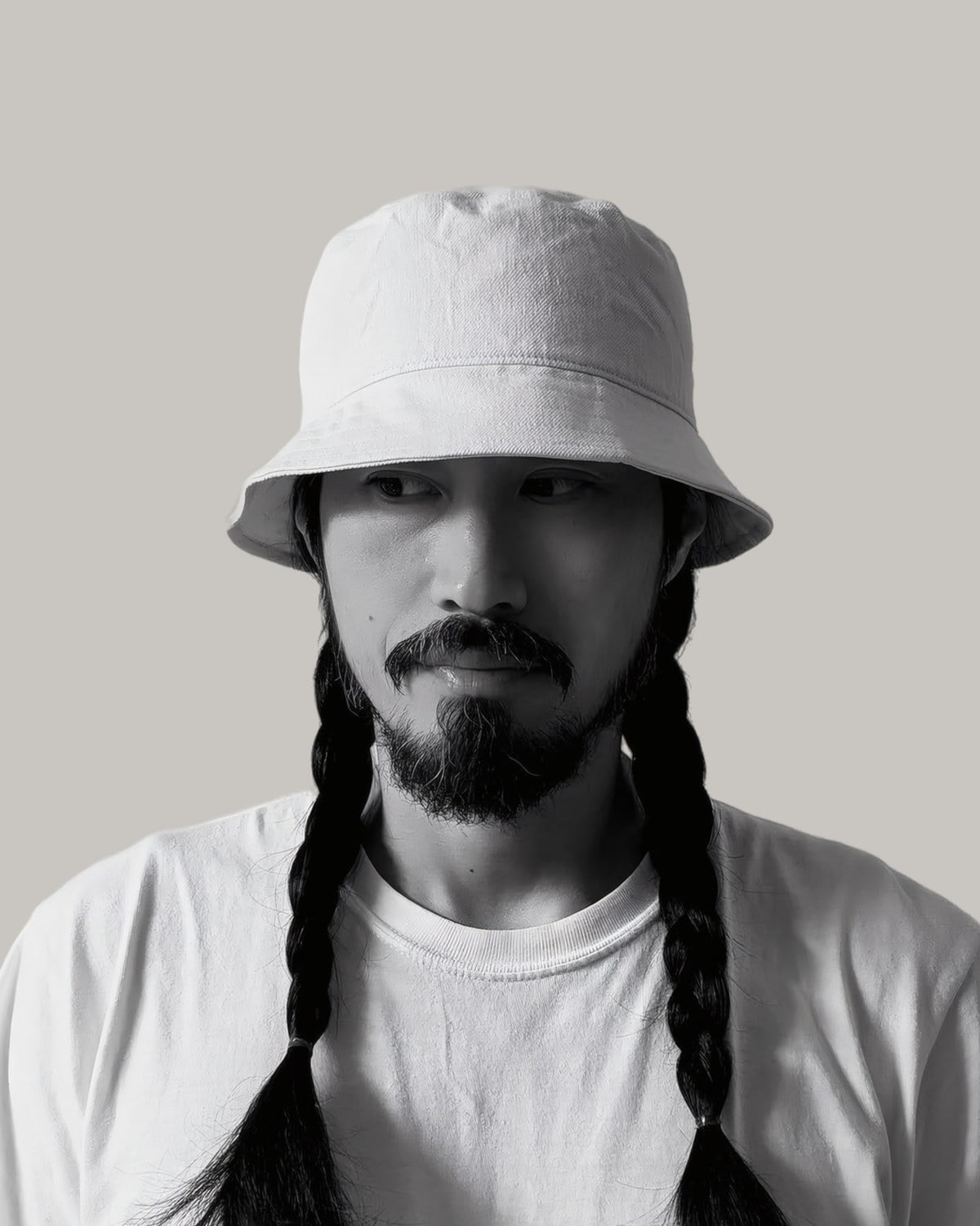 Bearded man in a bucket hat with his long hair in two braids