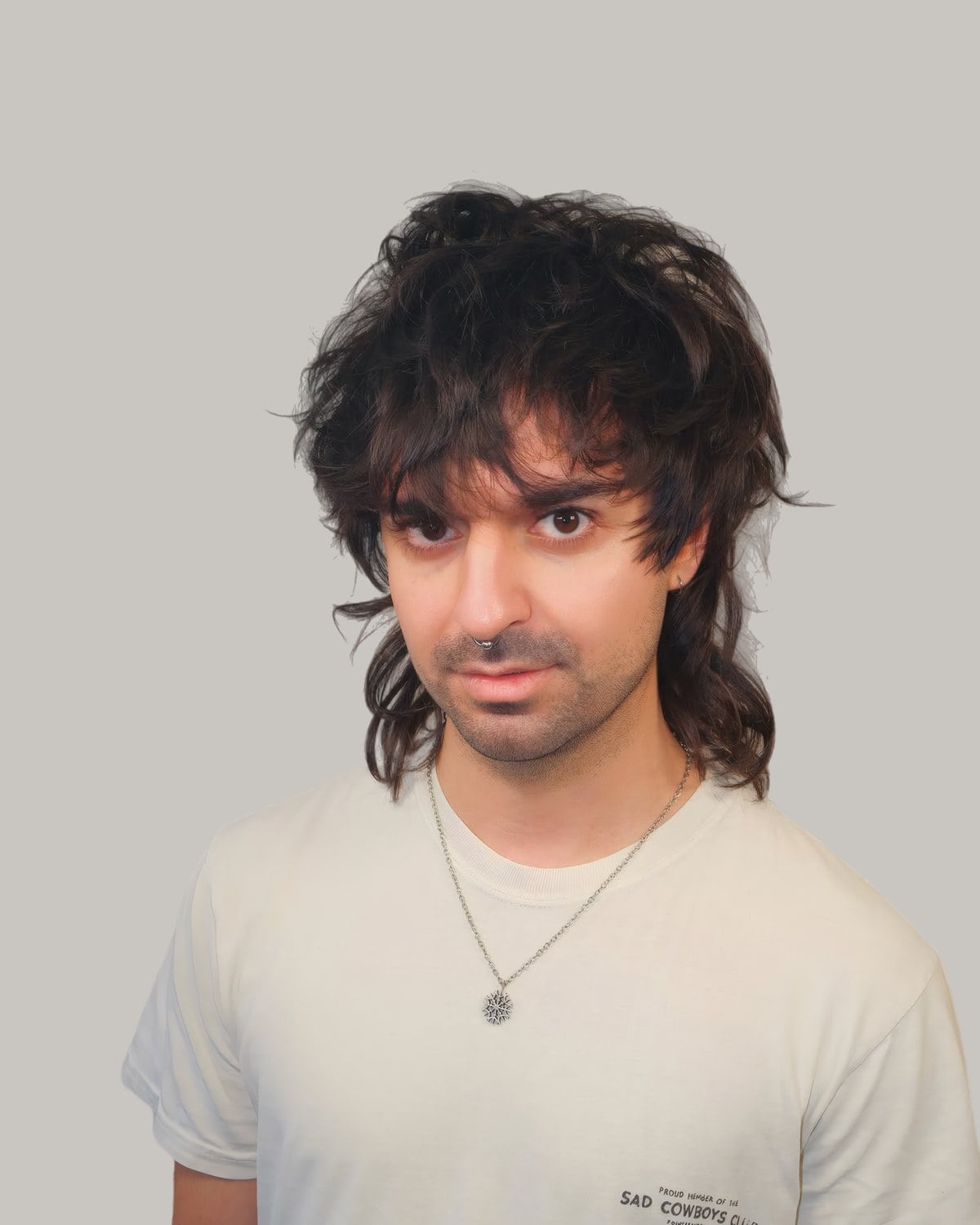 Man with a dark, shaggy cut, a choppy fringe and longer back
