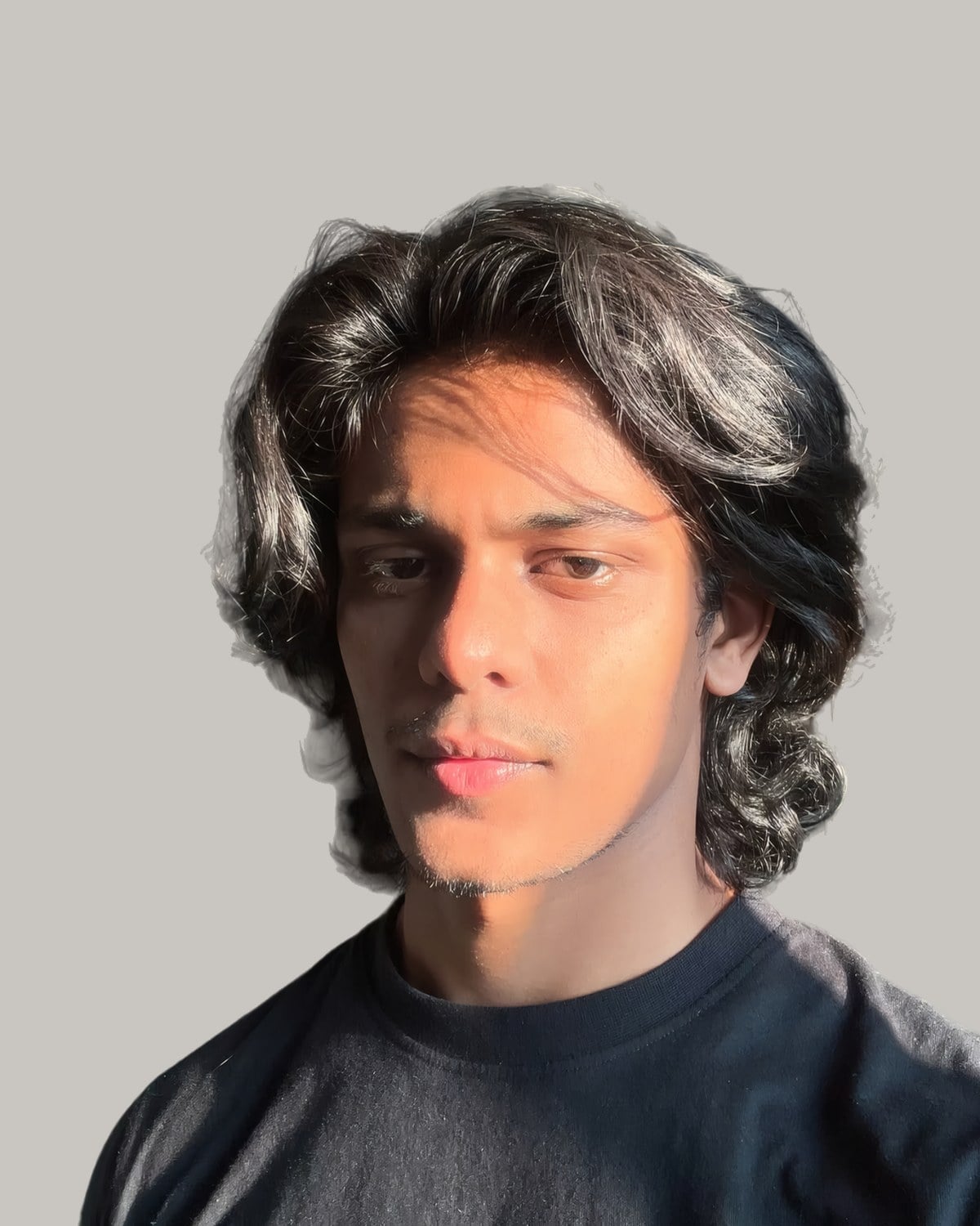 Young man with thick, messy dark hair falling to his shoulders