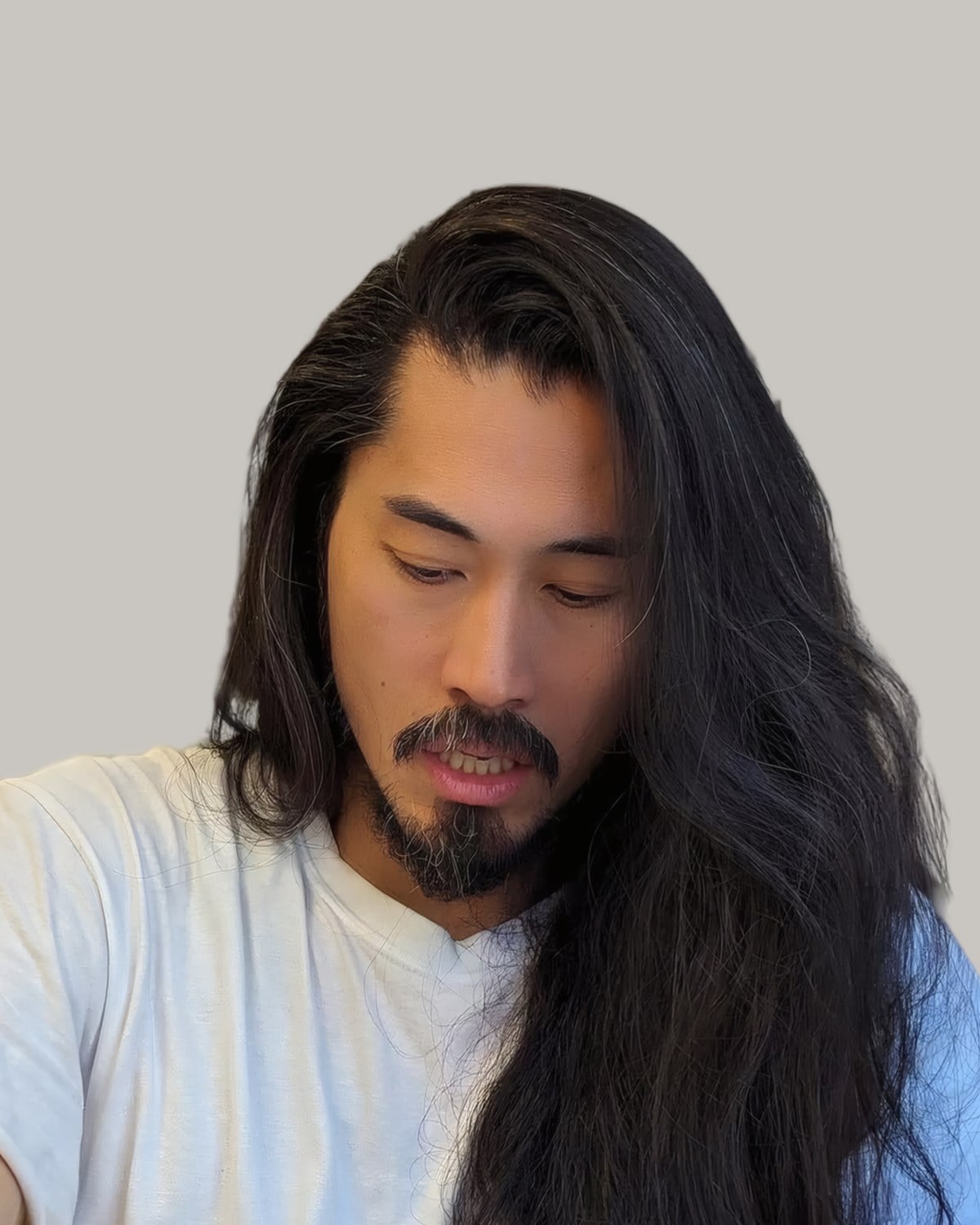Man with very long, straight black hair falling over his chest, head tilted down