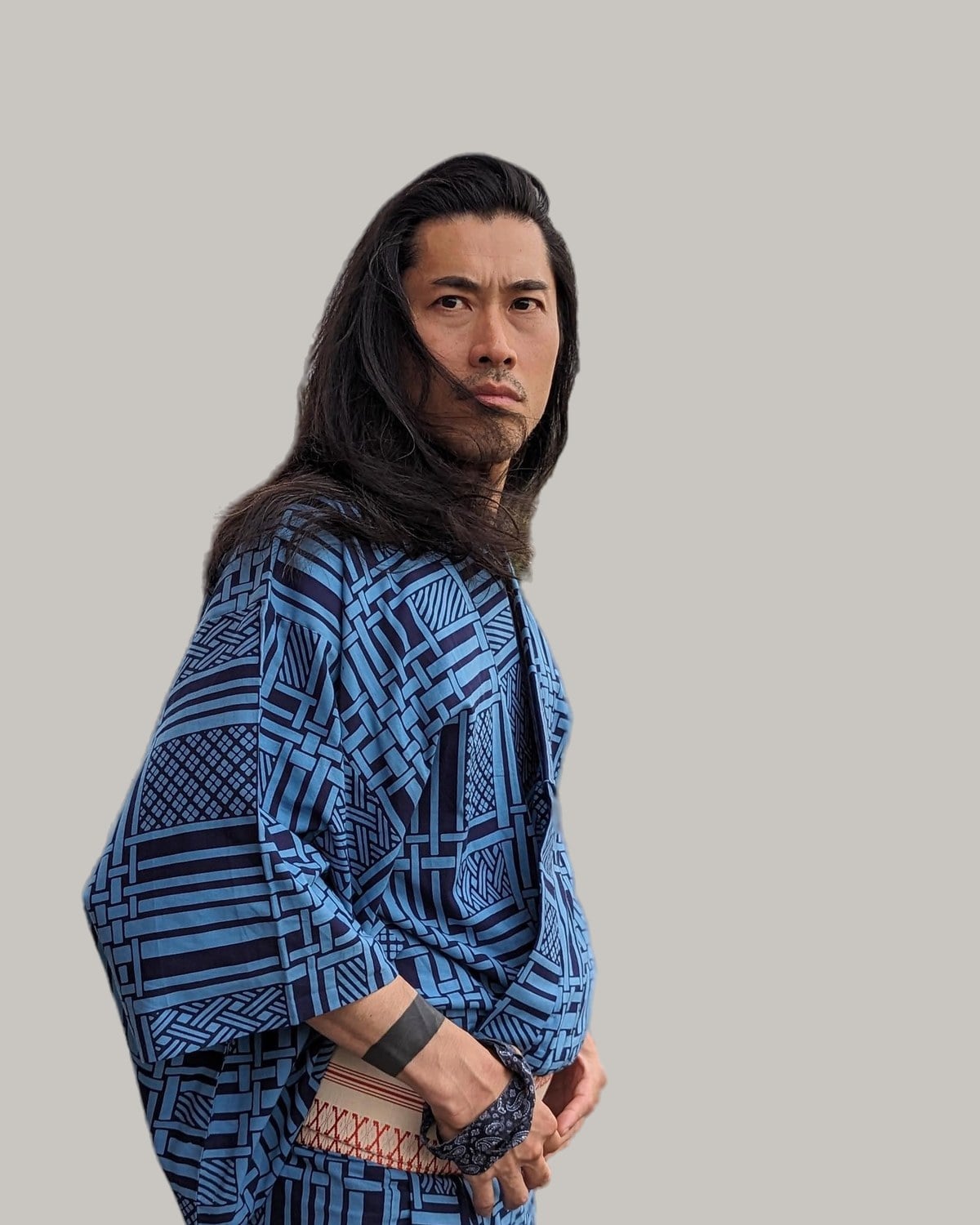 Man with long, straight black hair falling past his shoulders, seen outdoors