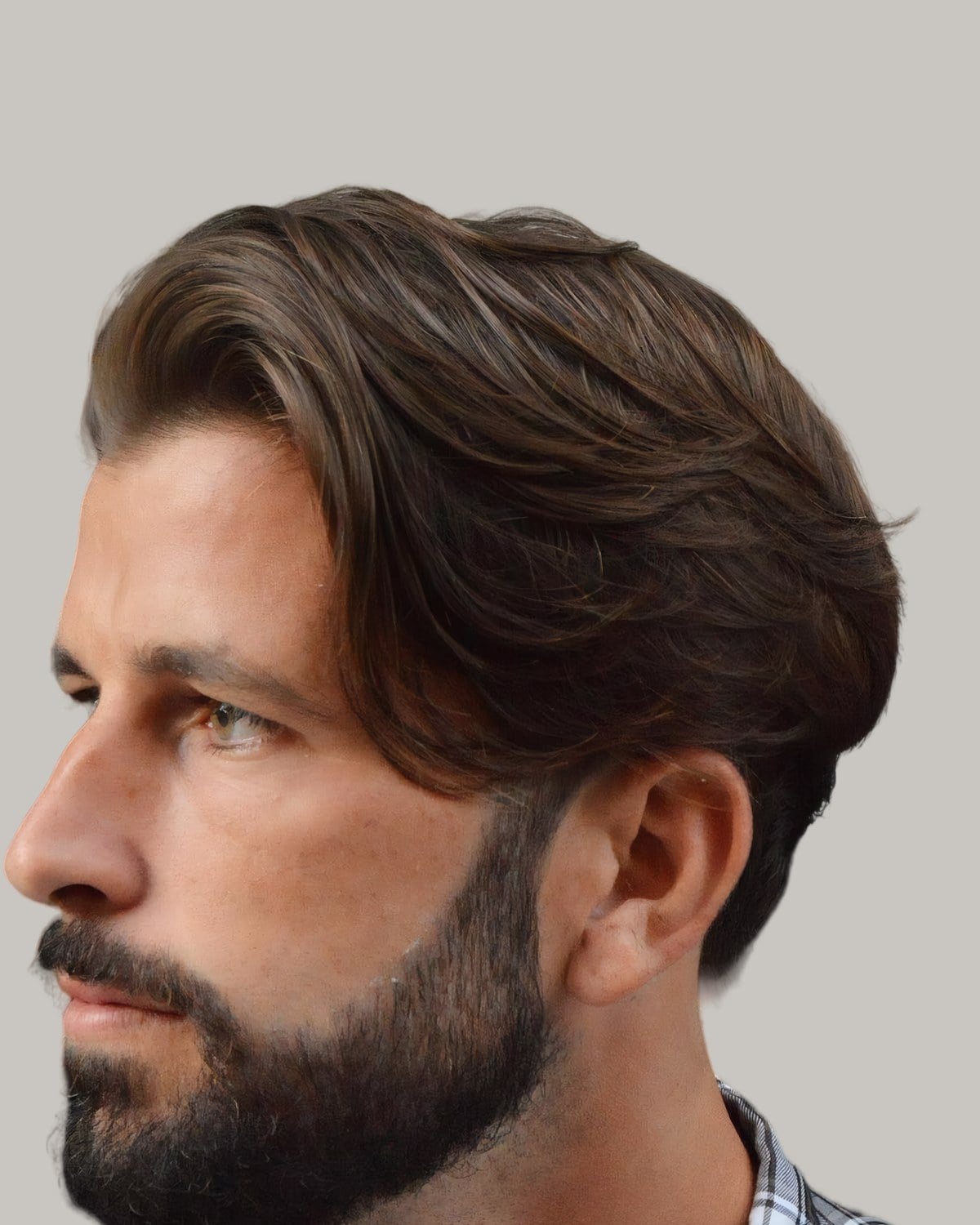 Bearded man with thick brown hair swept back from a side part, seen at an angle