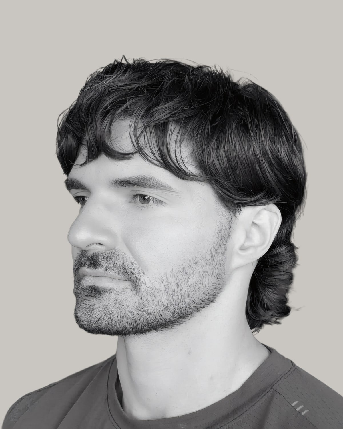 Man with dark wavy hair falling forward in a long swept fringe, in black and white