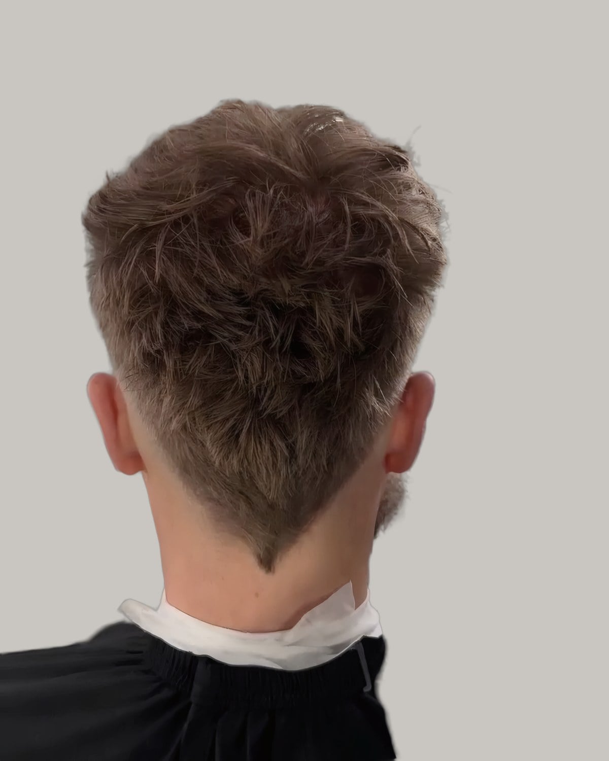 Man with a messy textured top and a taper at the neck, seen from behind