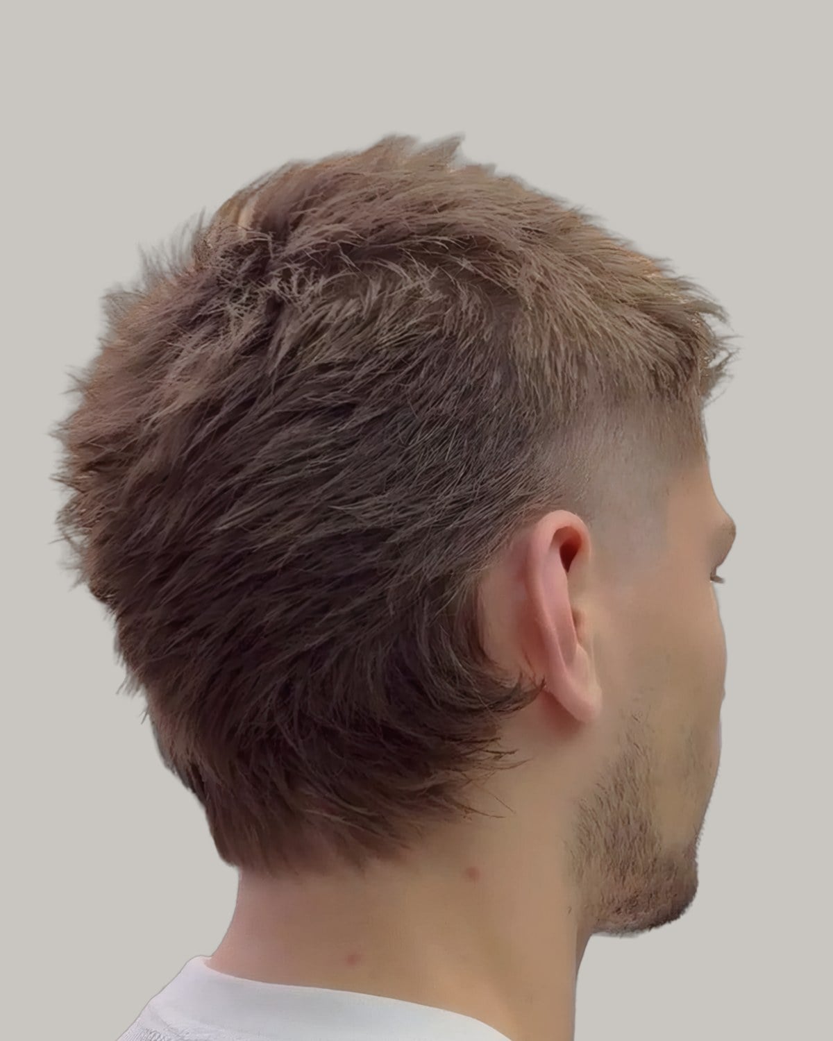Man with brown hair combed back and to the side, seen from behind at an angle, outdoors