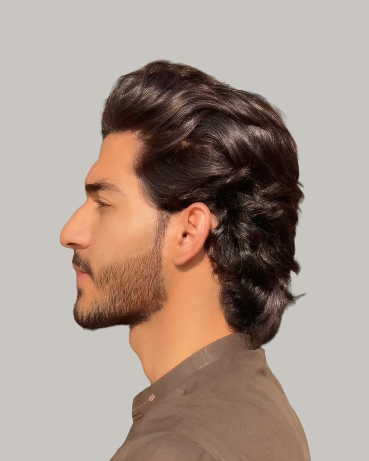 Bearded man with wavy dark hair to the collar, seen in profile outdoors