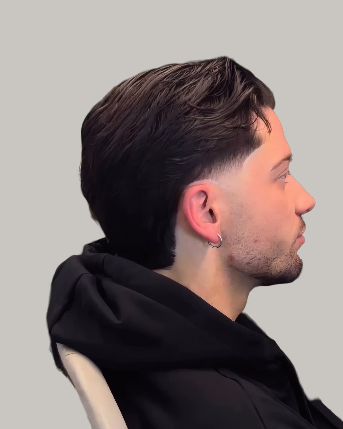 Man with dark hair swept back over faded sides, seen in profile